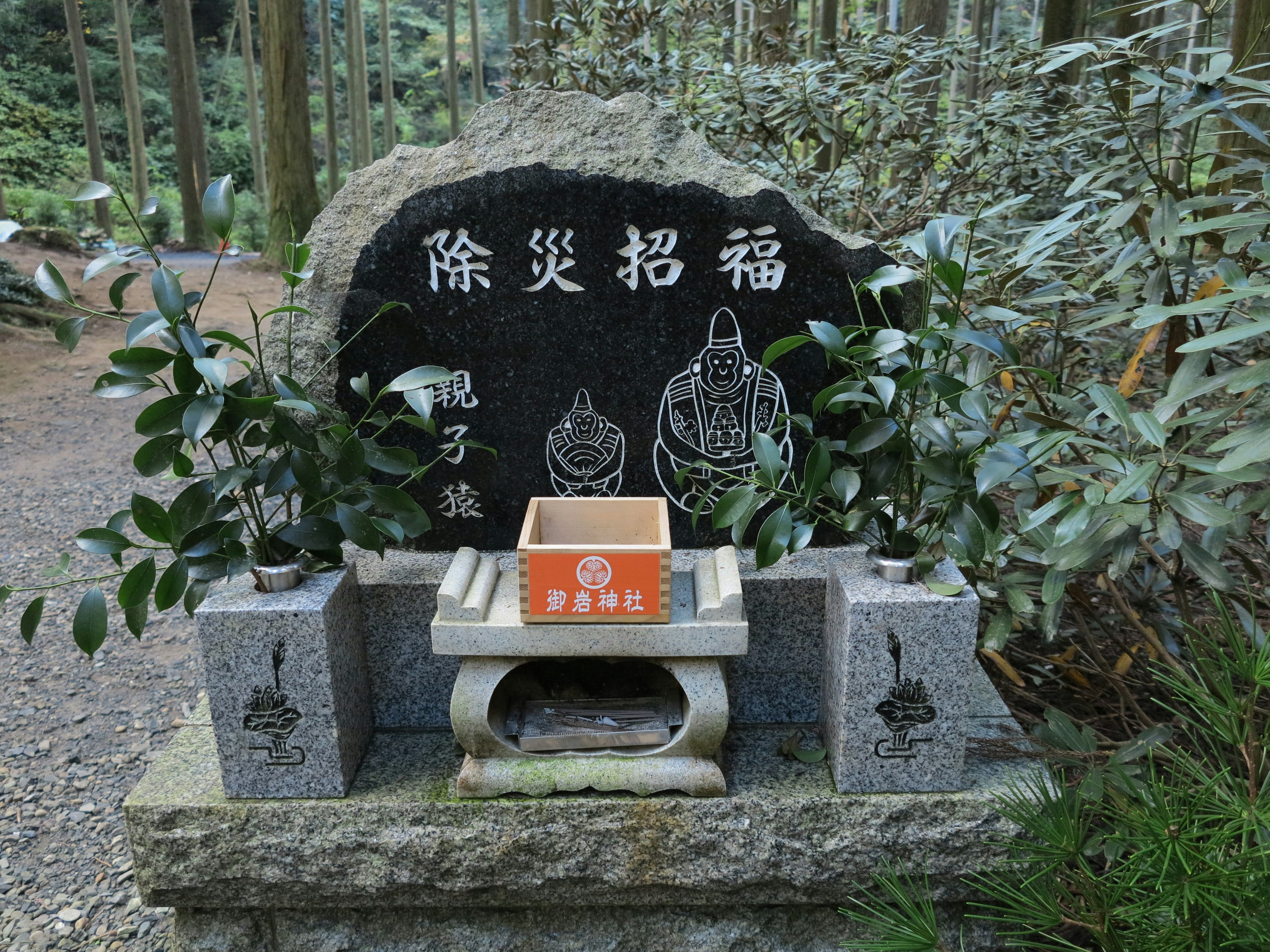 Steinaltar in einem Wald mit schwarzem Stein, der eingraviert ist und einem Buddha-Design