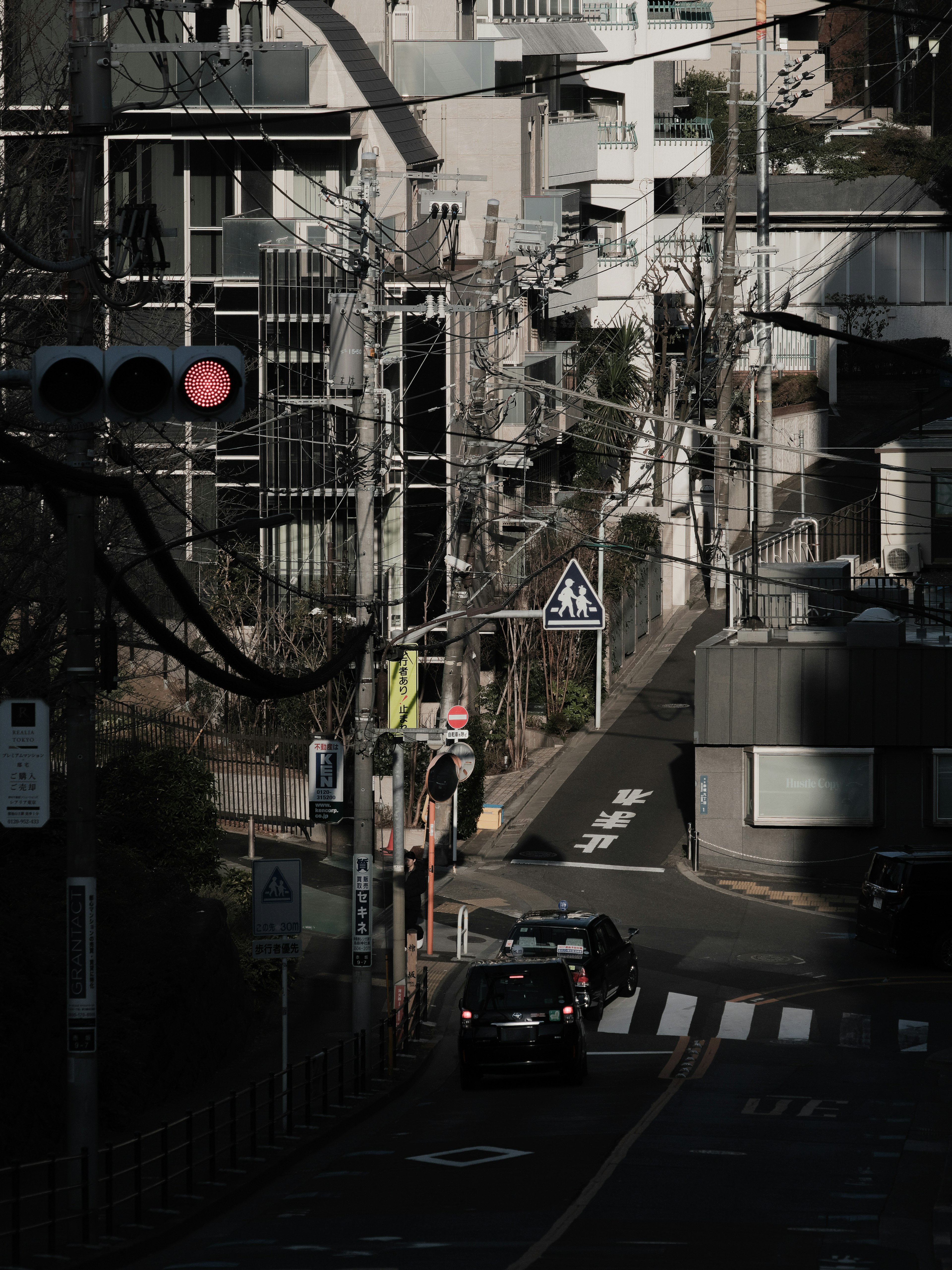 都市の狭い通りで車が走る風景 高層ビルと電柱が並ぶ