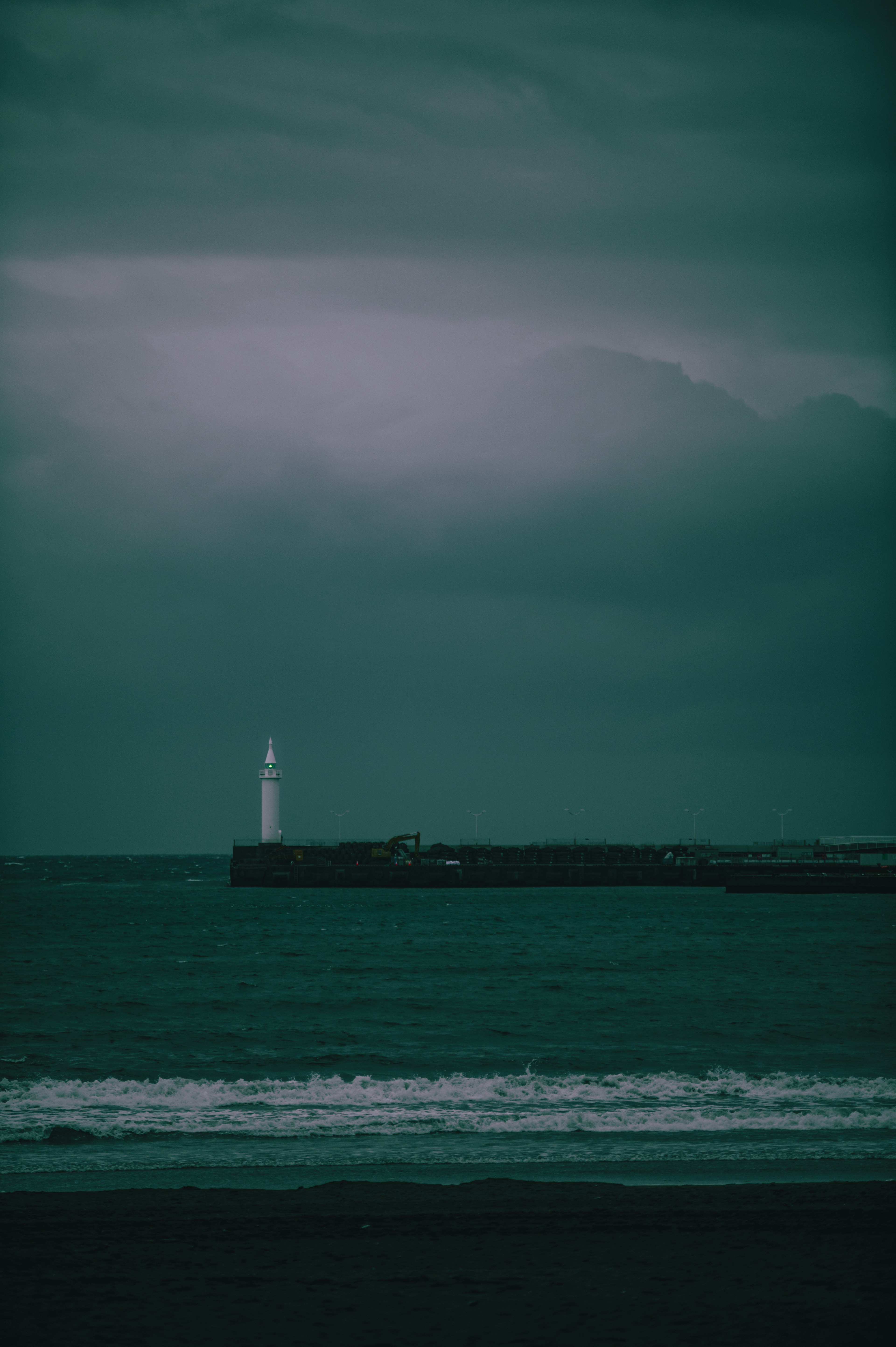 Moody seascape featuring a lighthouse and dark clouds