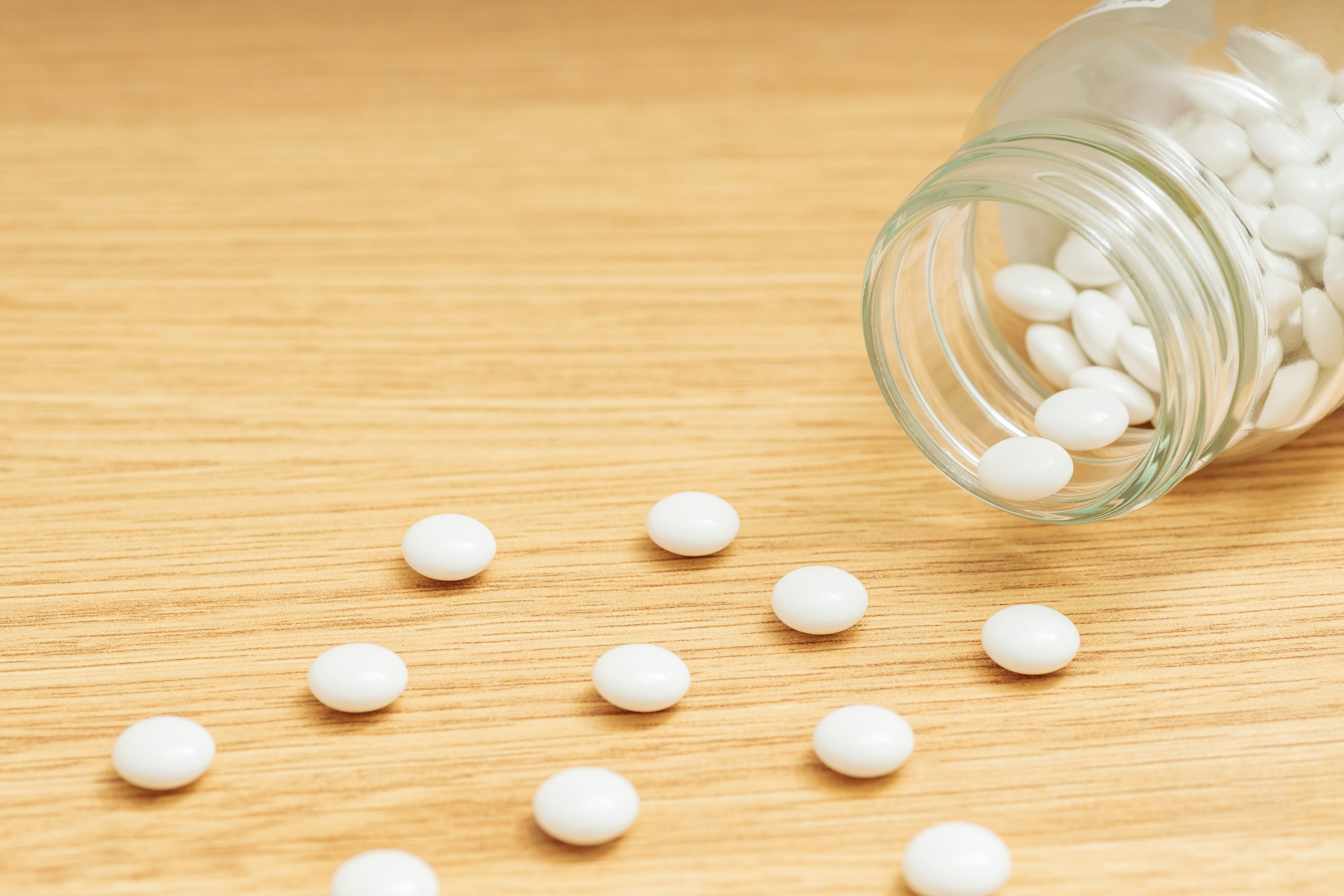 Image of white tablets scattered from a glass jar