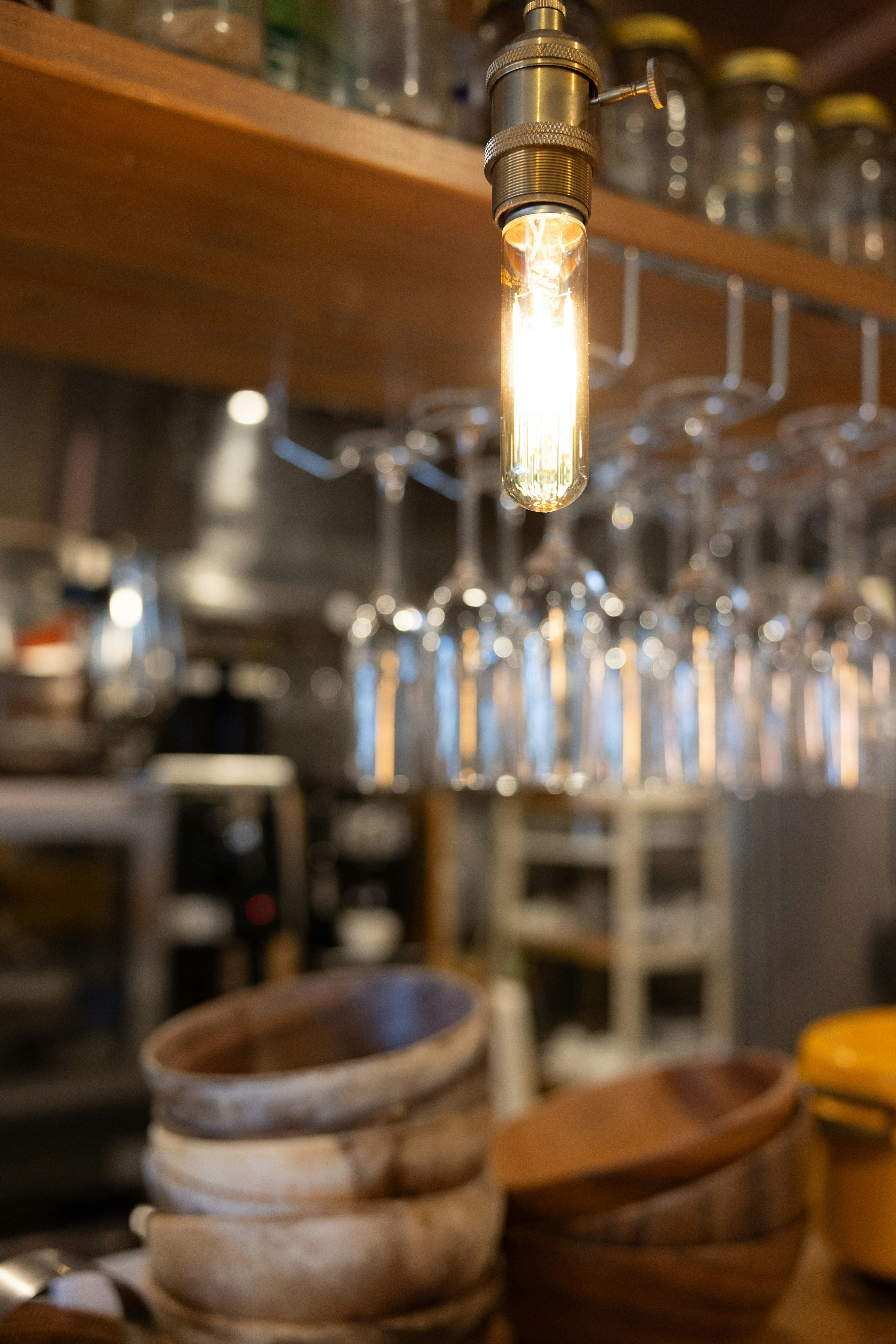 Interior de un café con cuencos de madera y copas colgantes con una bombilla prominente