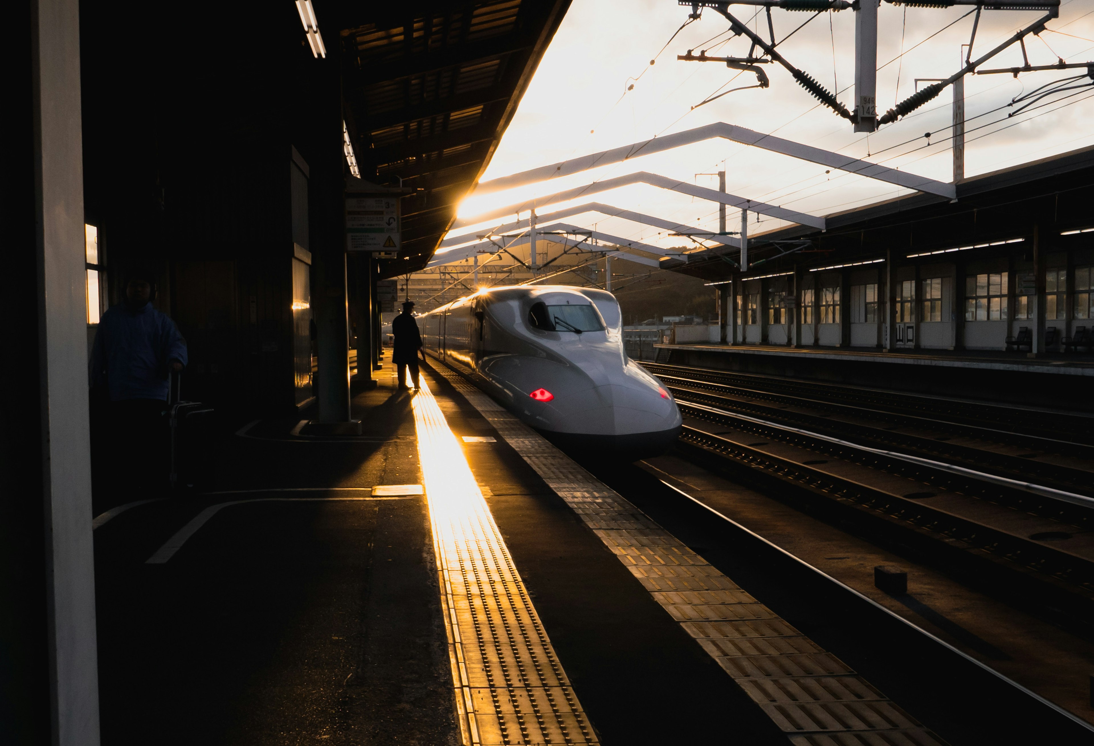 Shinkansen arriving at the station with sunset in the background