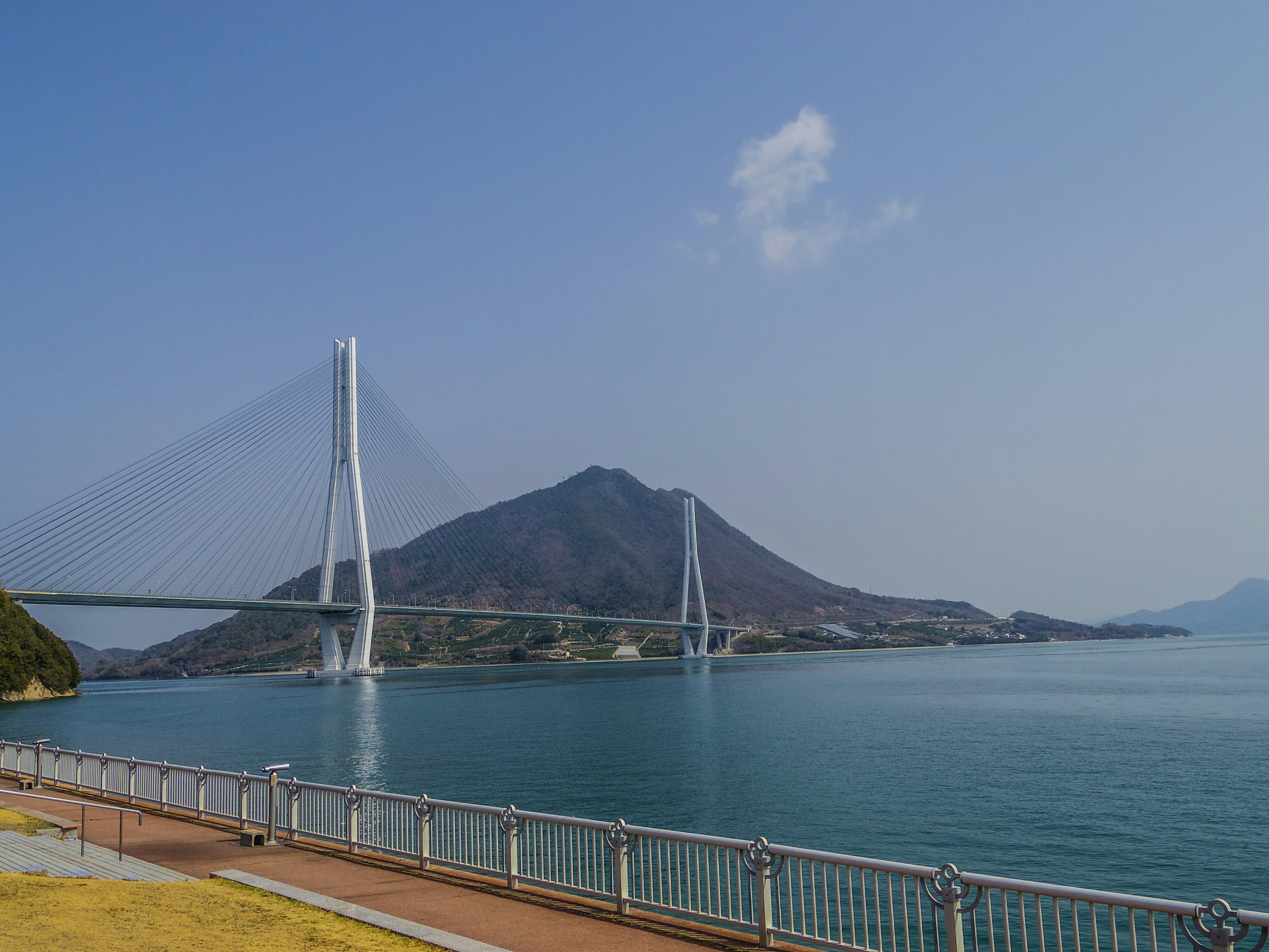 Vue pittoresque d'un pont à haubans sur des eaux calmes avec une montagne en arrière-plan