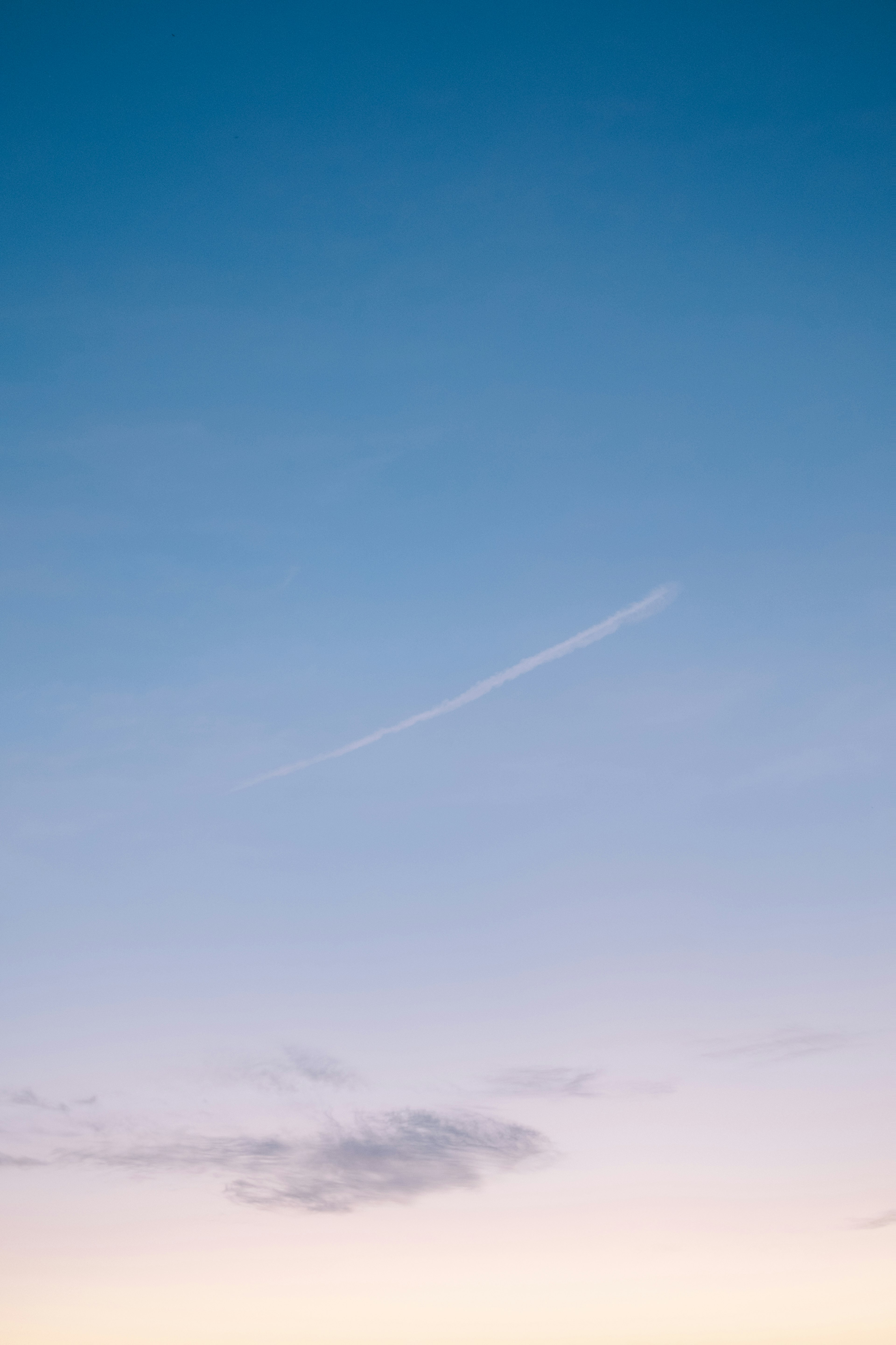 Ein ruhiger Himmel mit sanften Wolken und einer leichten Spur