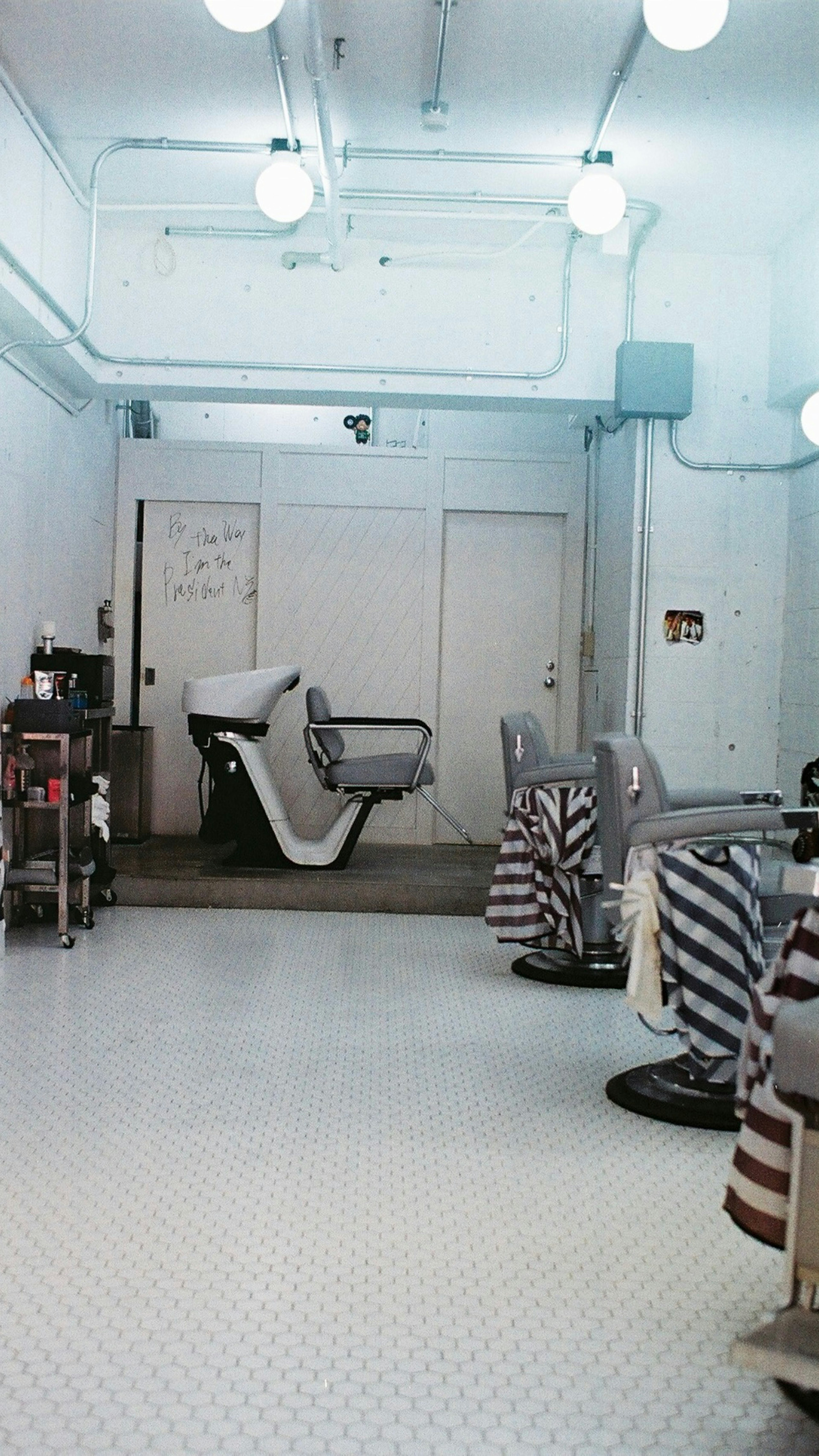 Interno di un barbiere con pareti e pavimento bianchi sedie a strisce disposte in un design semplice e pulito