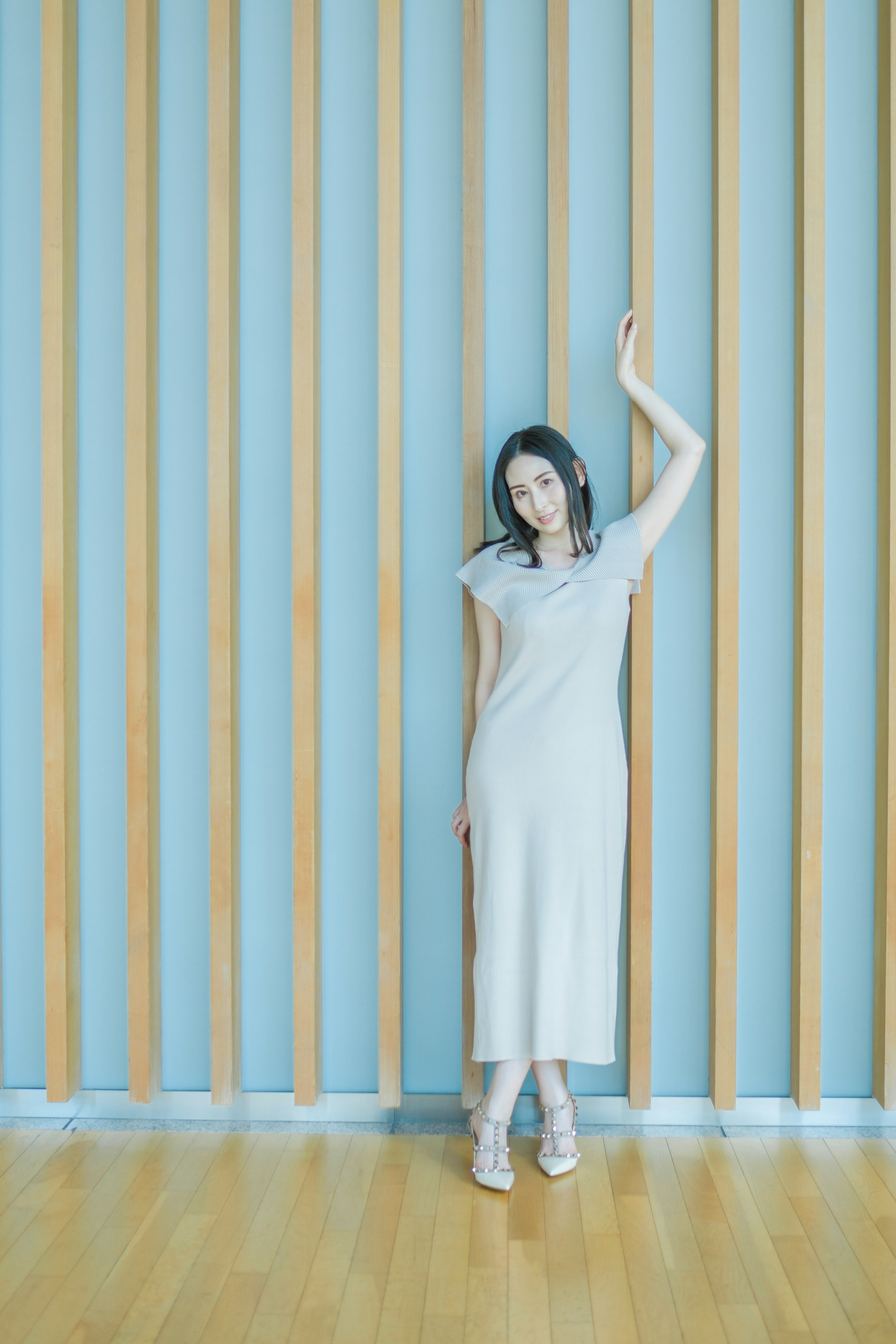 Foto de moda de una mujer de pie frente a una pared azul