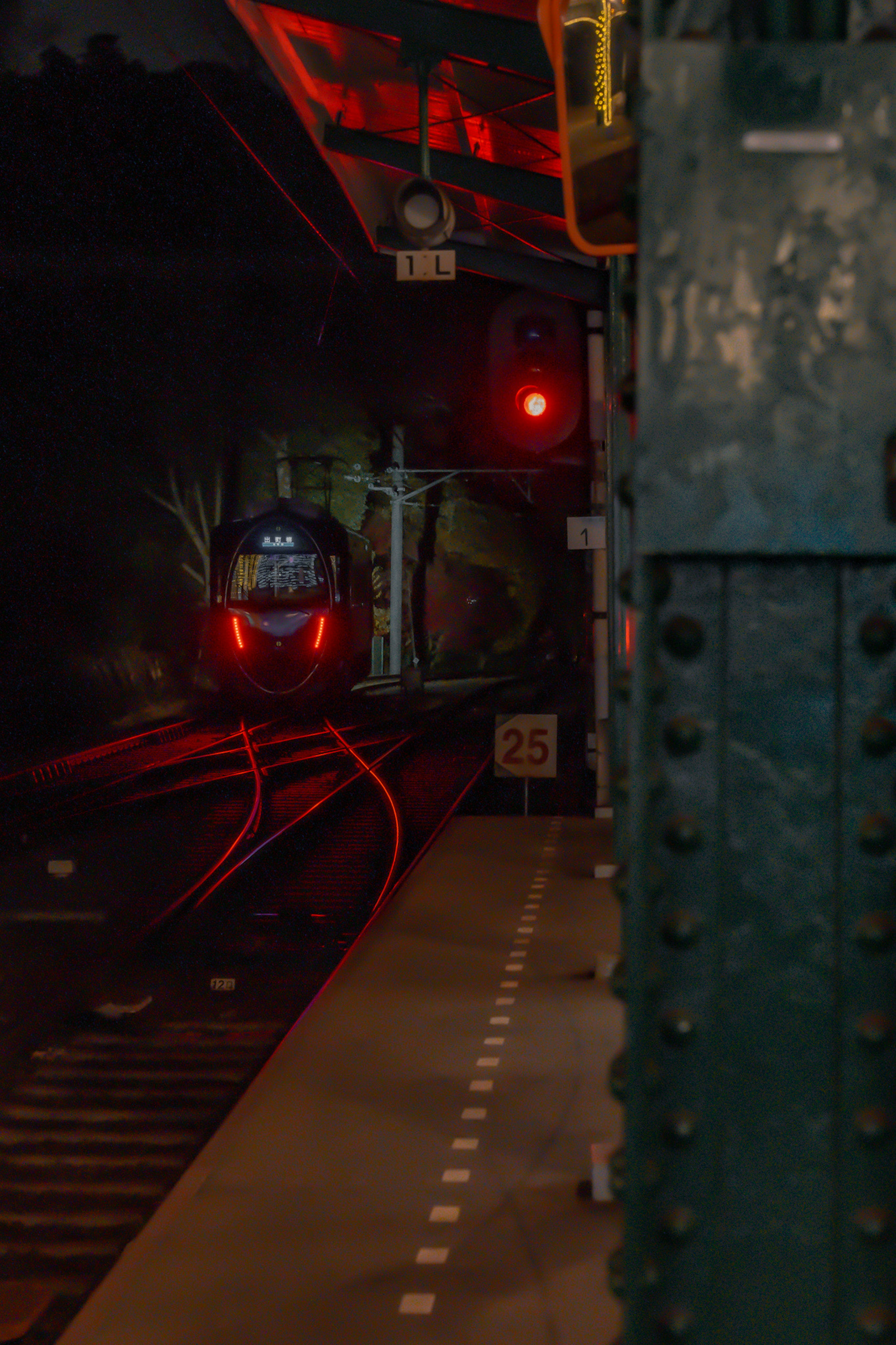 Una foto di un treno fermo a un segnale rosso in una stazione buia