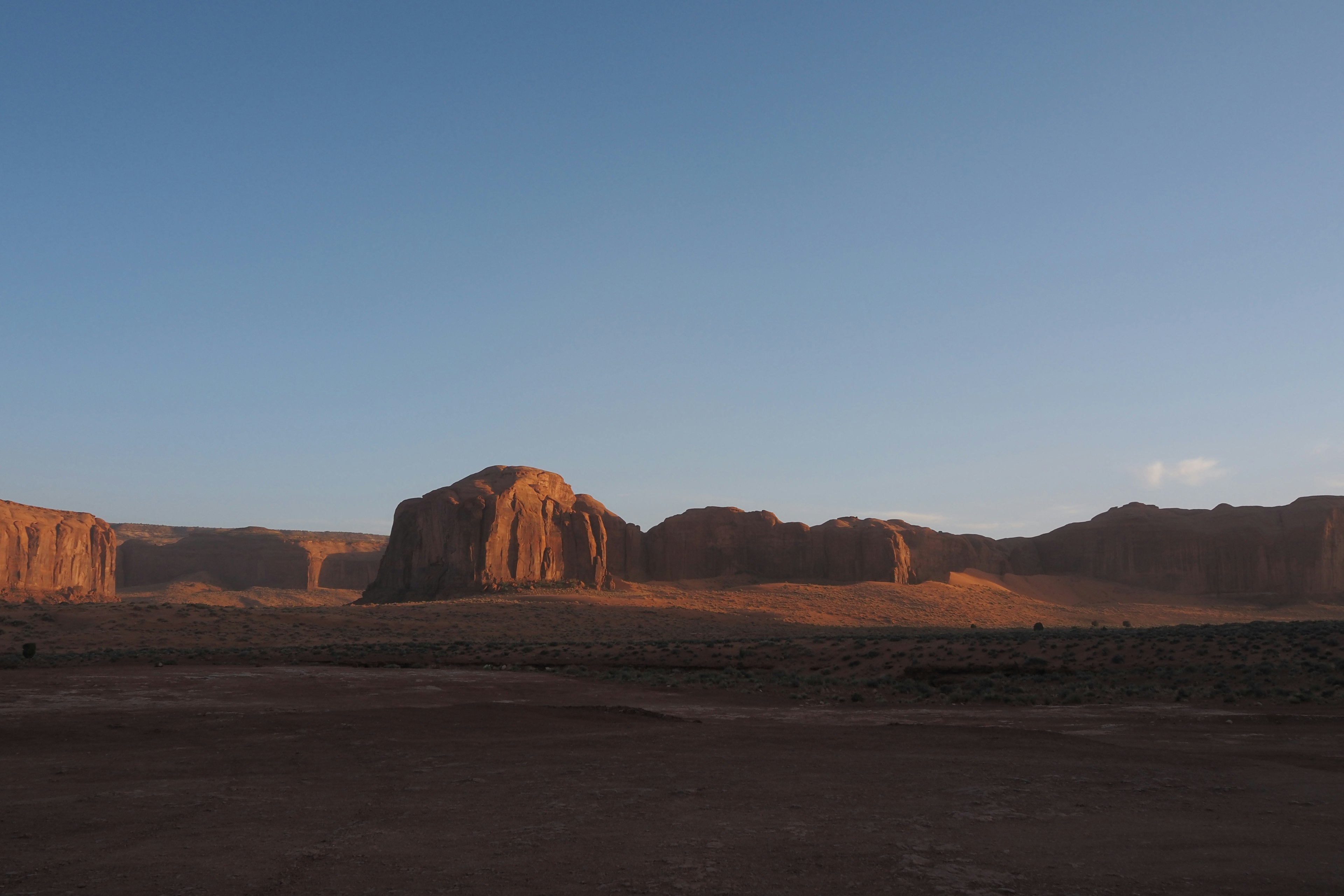 Amplio paisaje desértico con majestuosas formaciones rocosas iluminadas por el atardecer