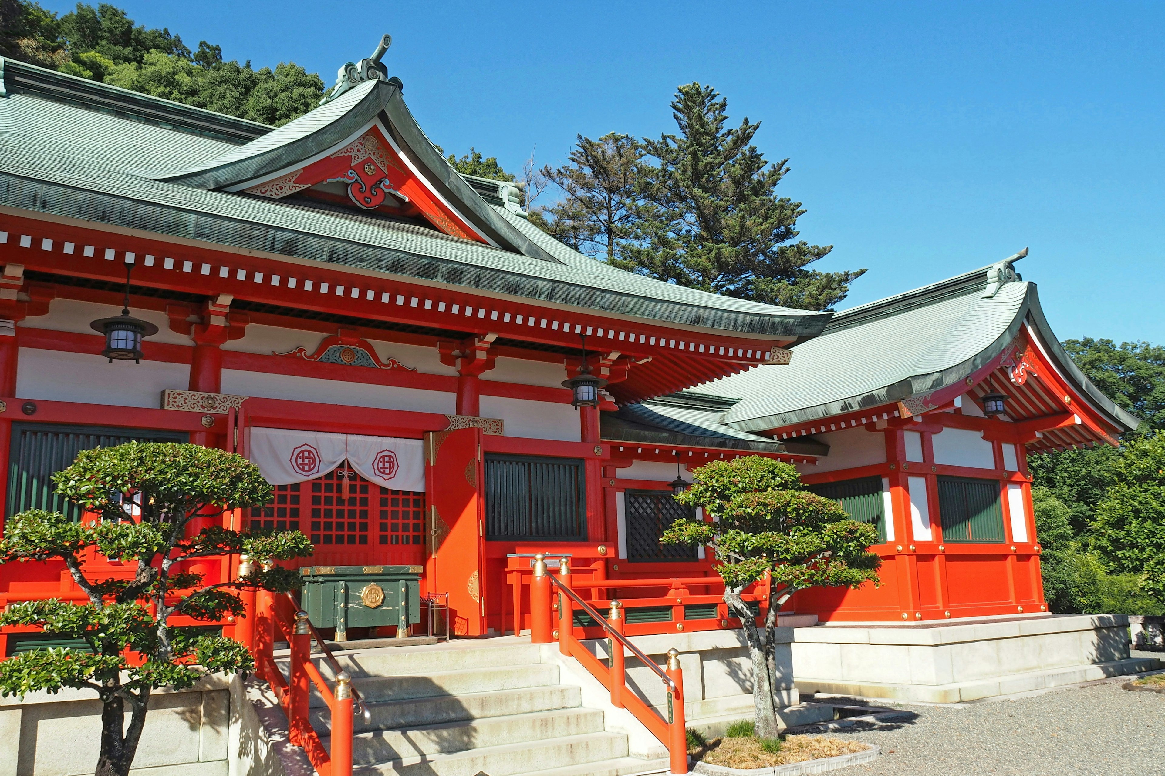 传统日本神社，红色屋顶和修剪整齐的树木