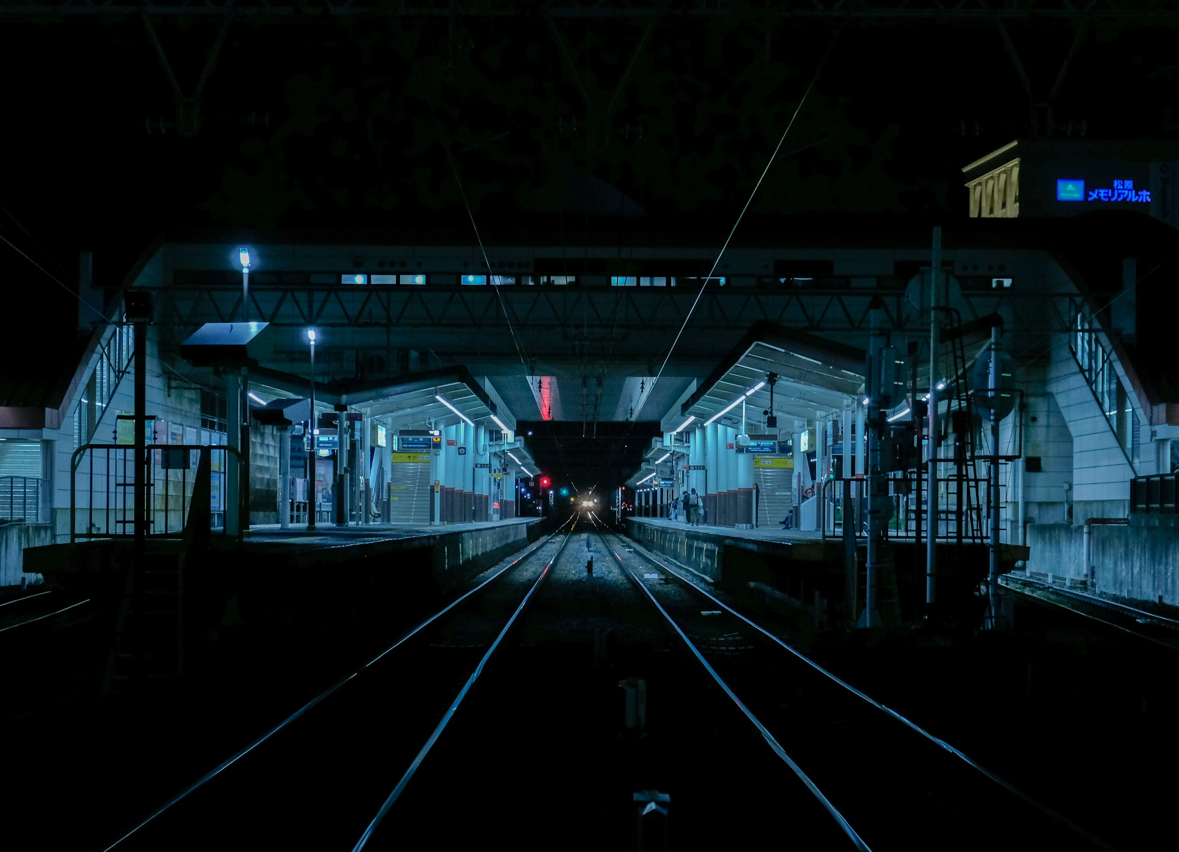 Vue nocturne d'une plateforme de gare avec des rails éclairés