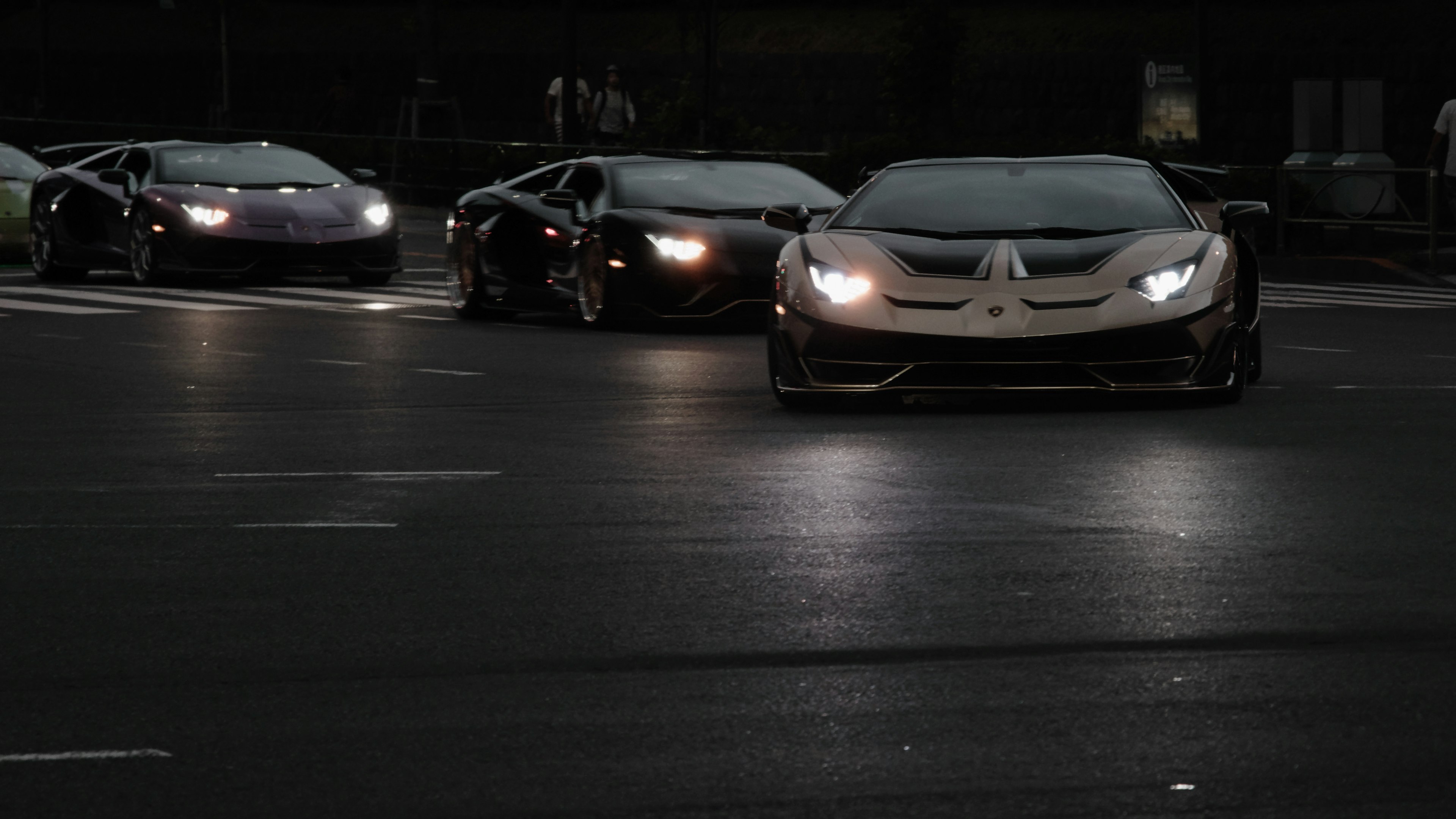 A group of luxury sports cars racing on a city street at night