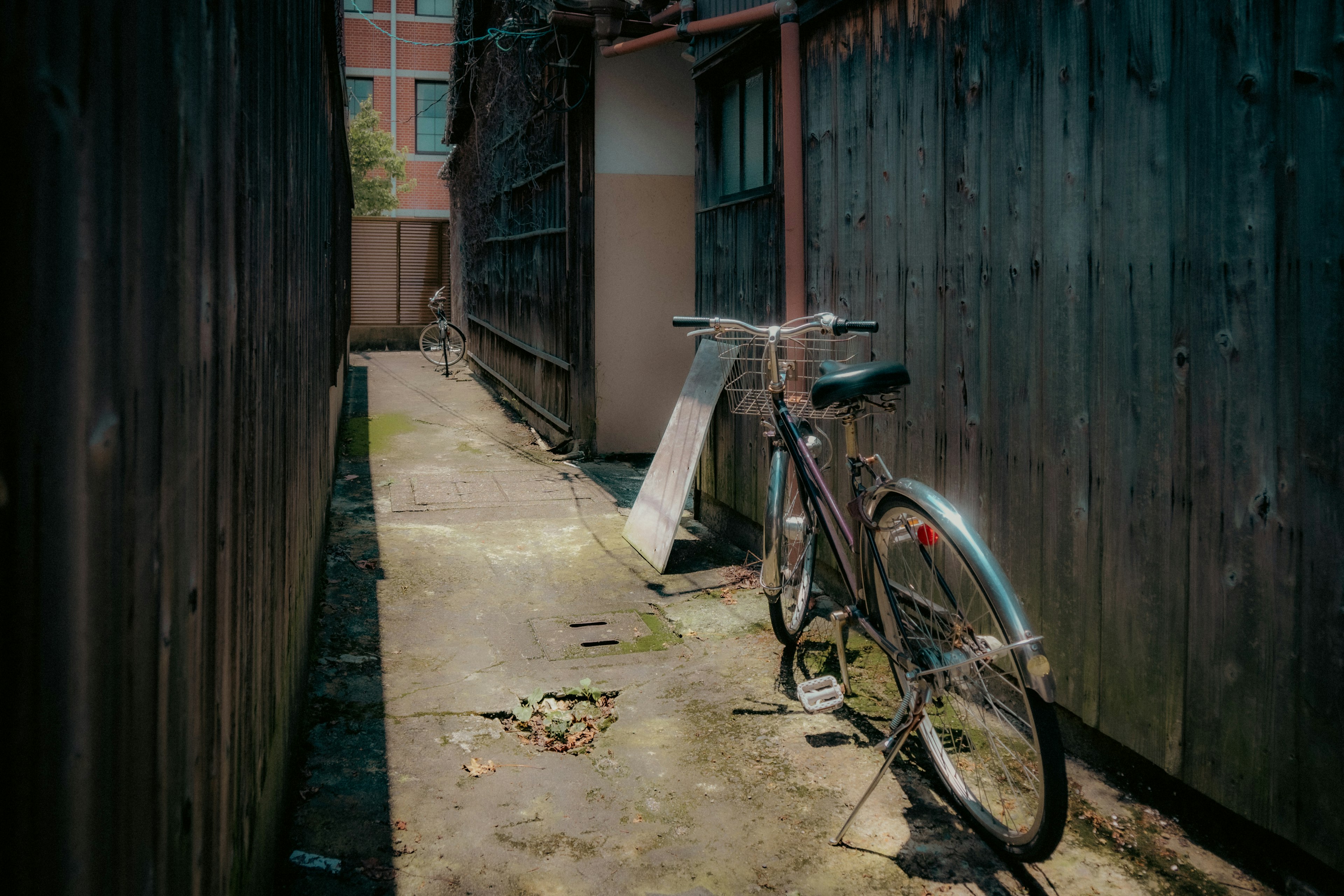 A bicycle parked in a narrow alley with wooden fences