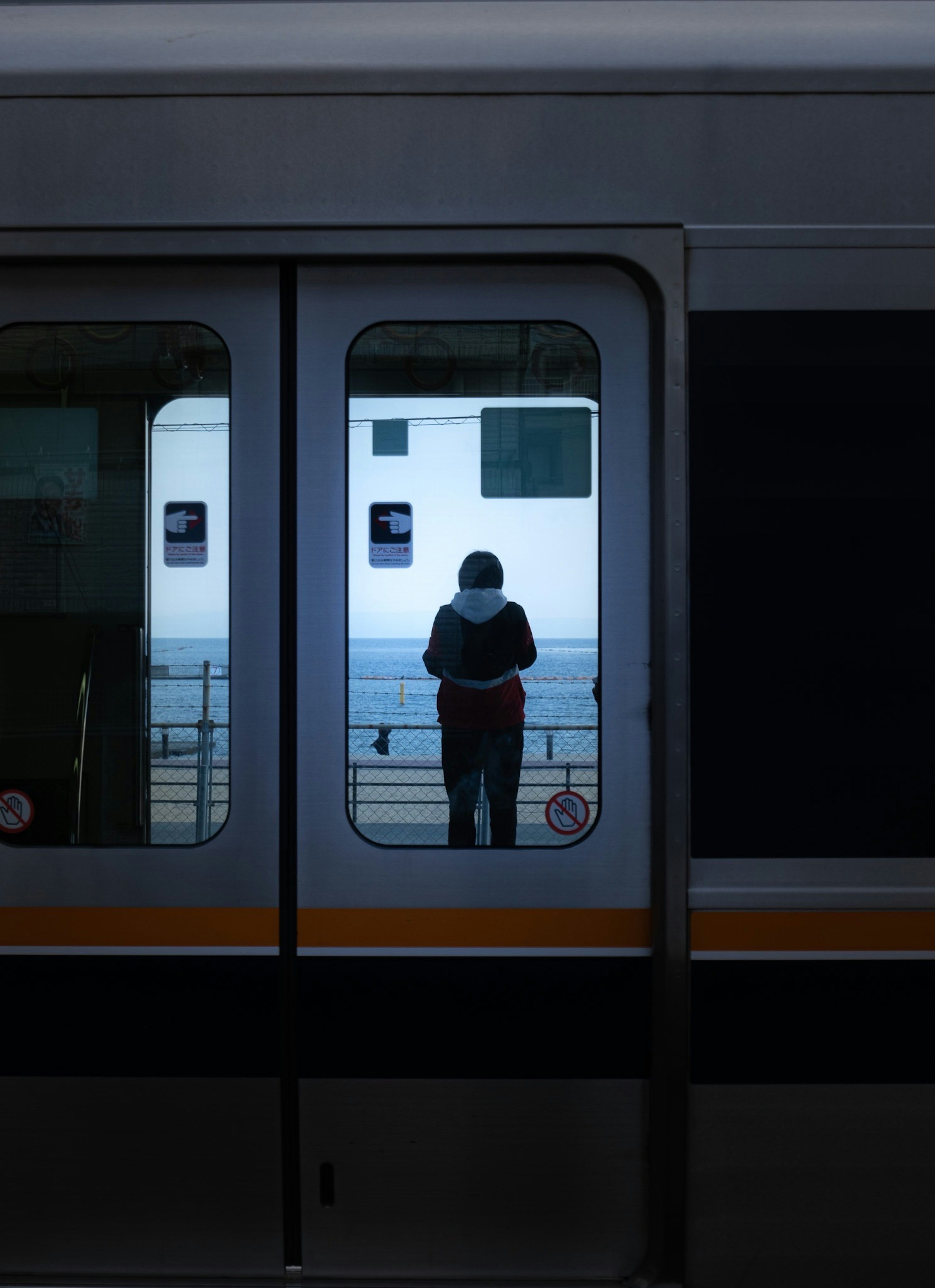 電車の窓から見える人影と背景の海