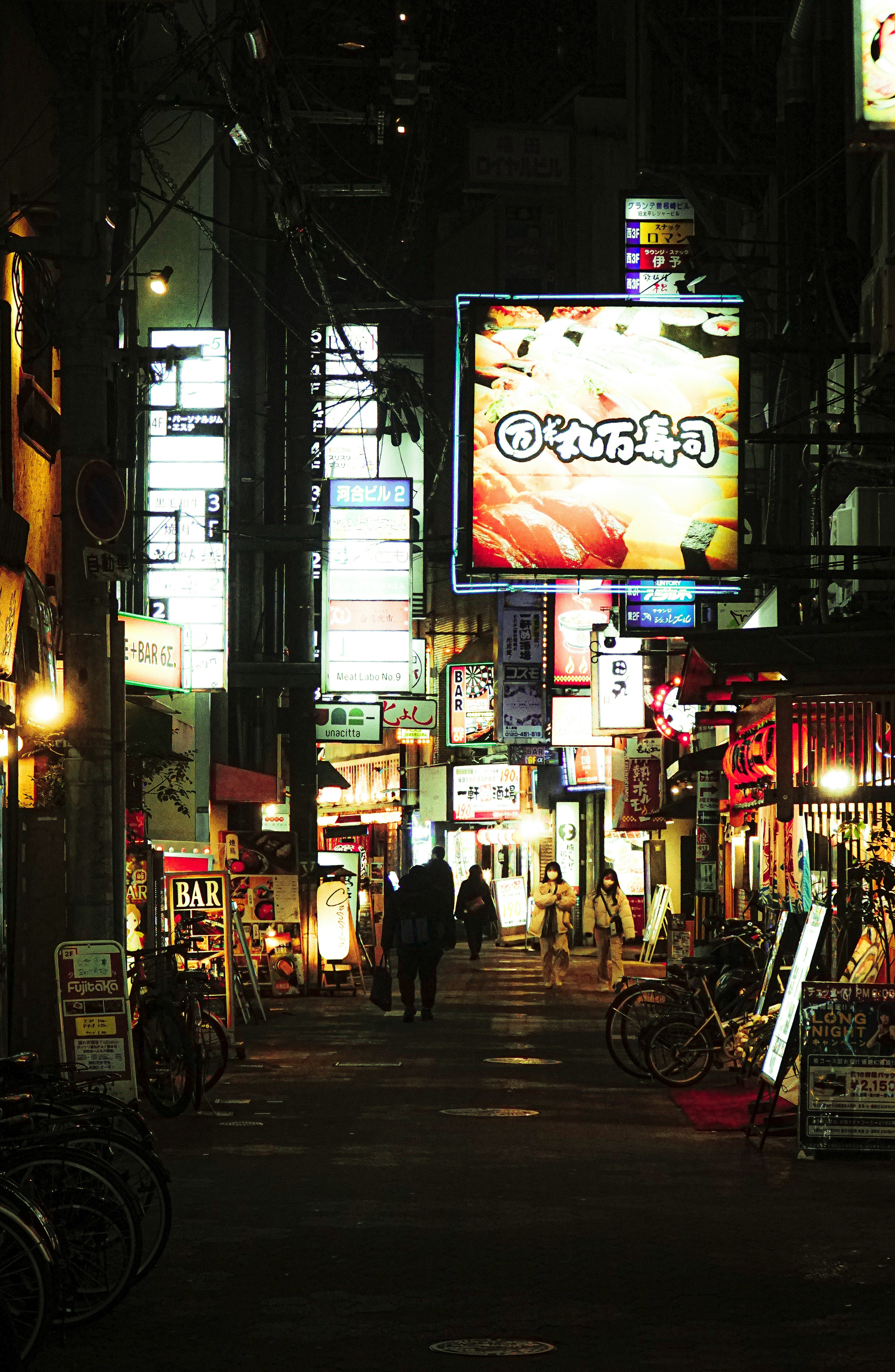 Una calle estrecha iluminada por letreros de neón coloridos por la noche