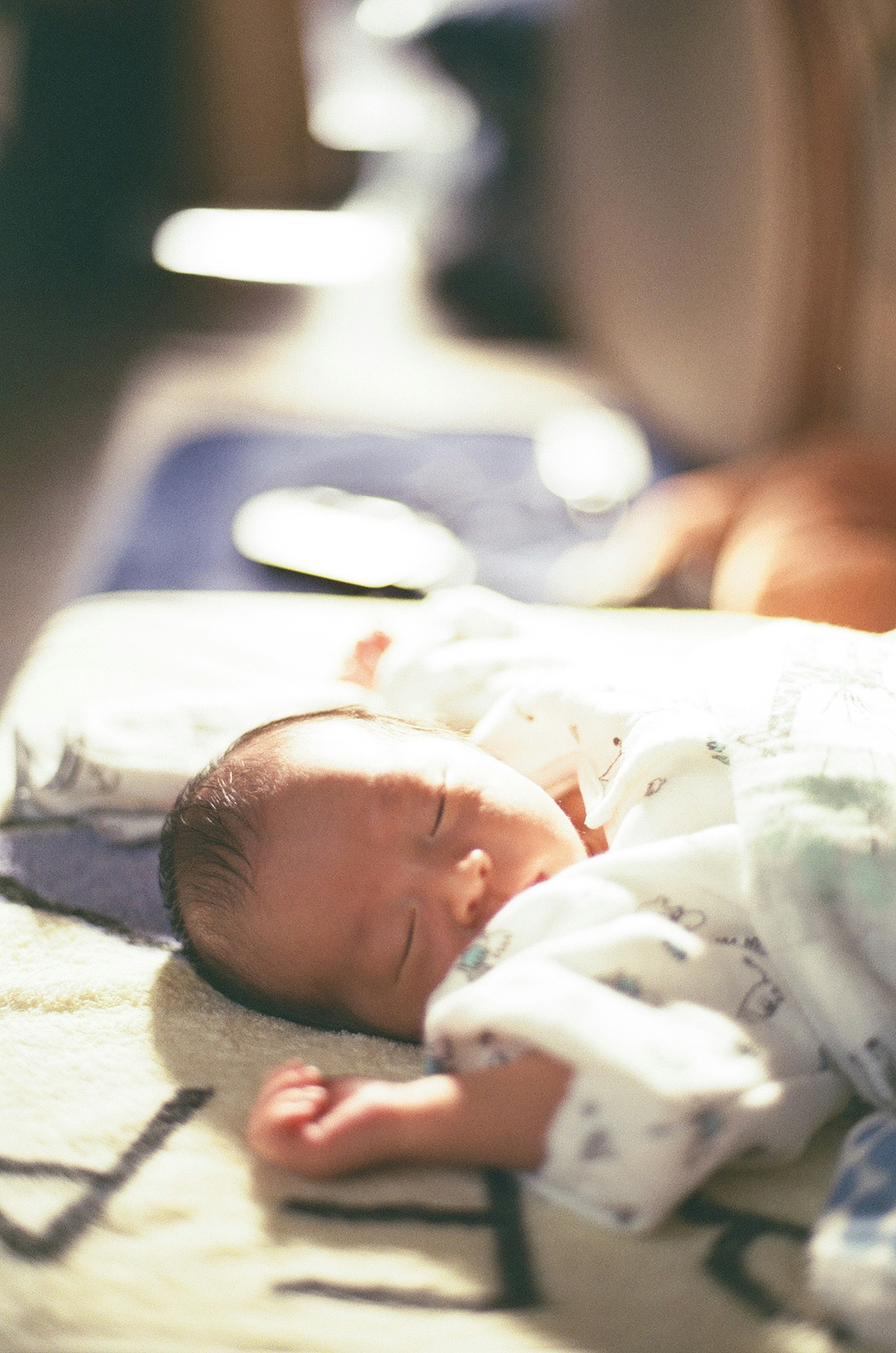 Un bambino che dorme su una superficie morbida indossando abiti chiari