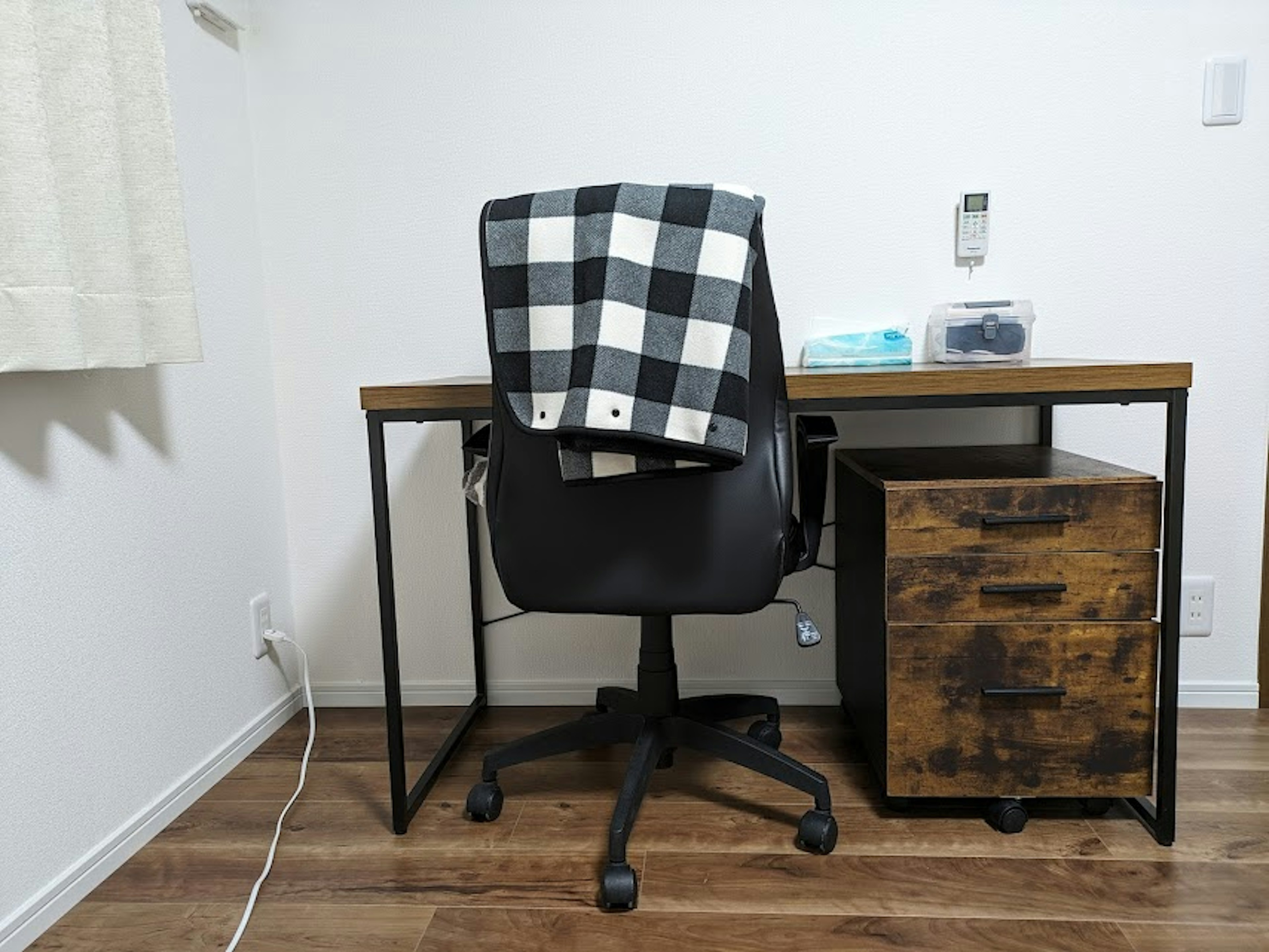 Un bureau simple avec une chaise noire et une couverture à carreaux noir et blanc dessus