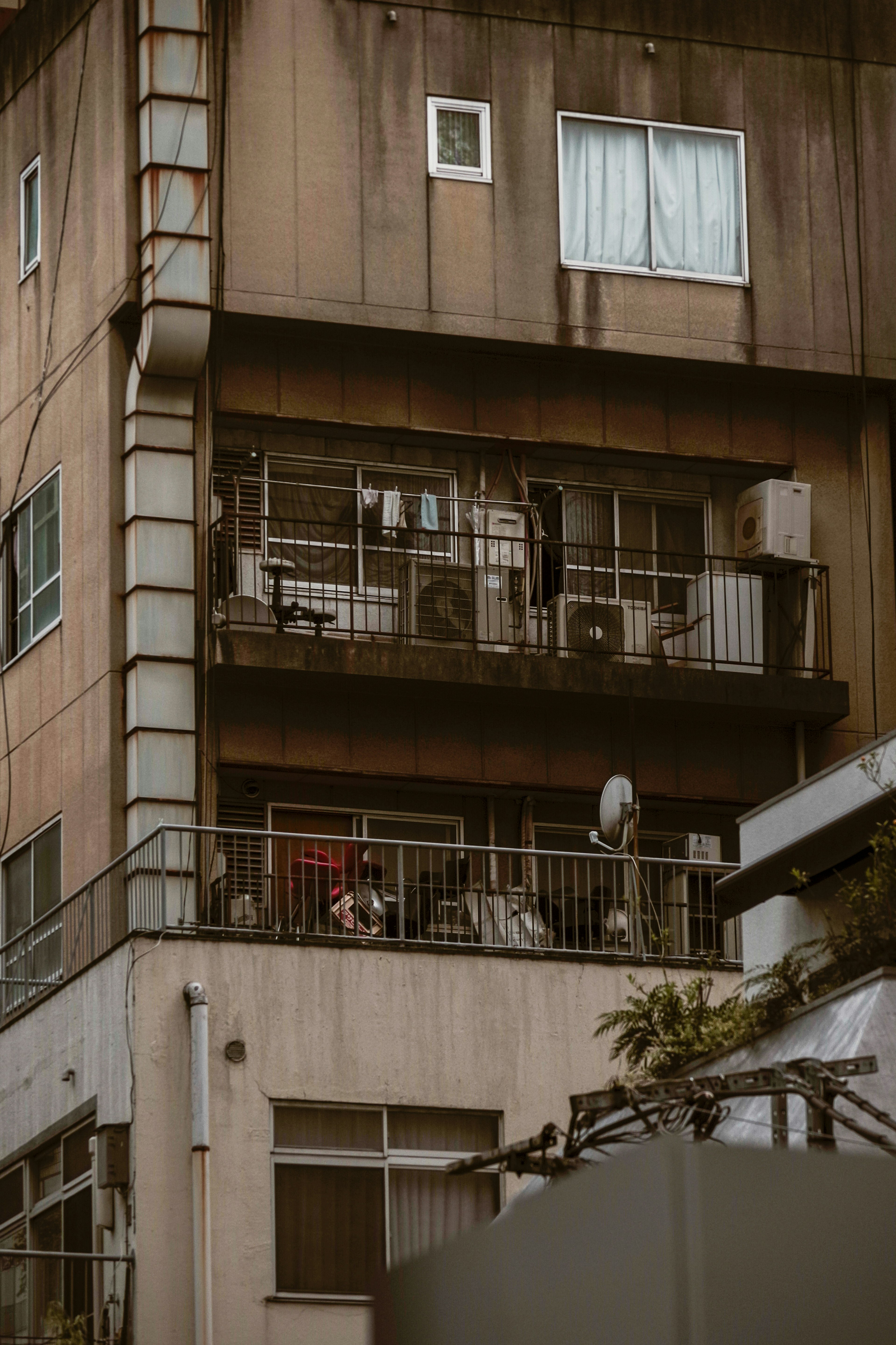 Eksterior gedung apartemen tua dengan balkon yang menampilkan pakaian