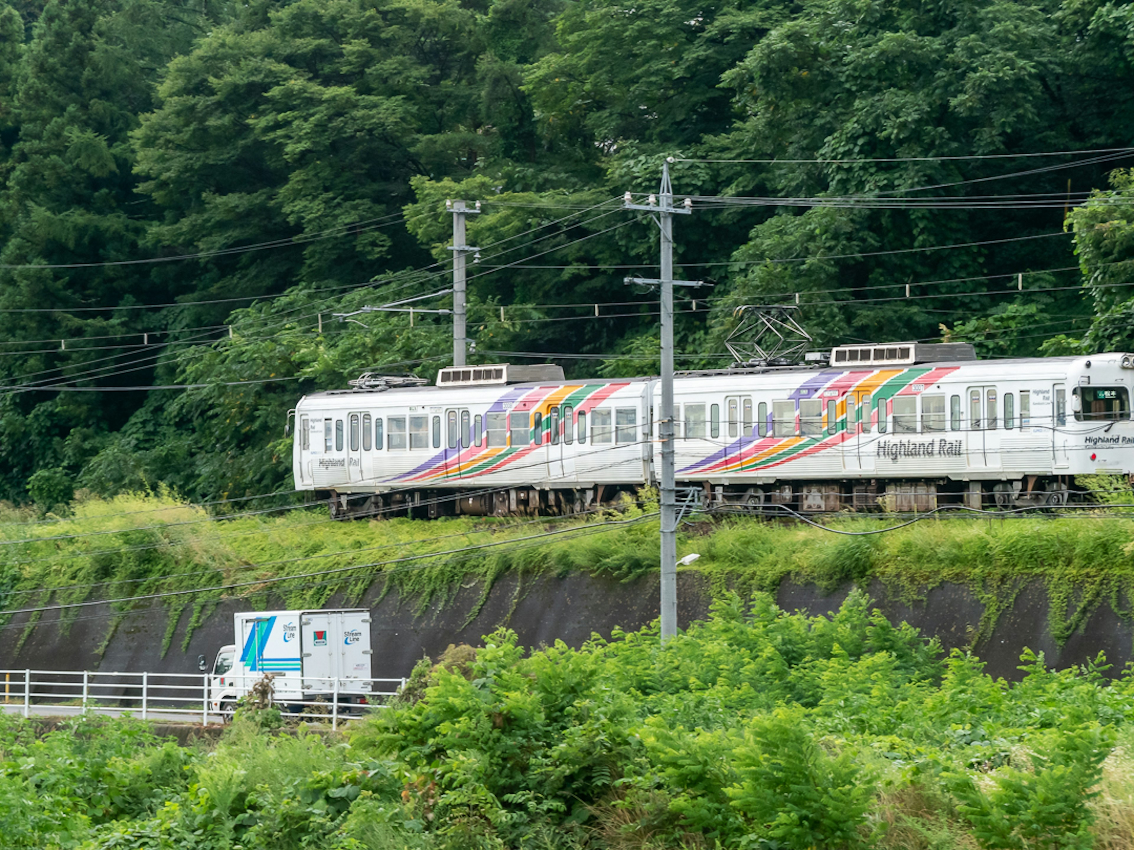 Ein bunt gestreifter Zug, der durch eine grüne Landschaft fährt