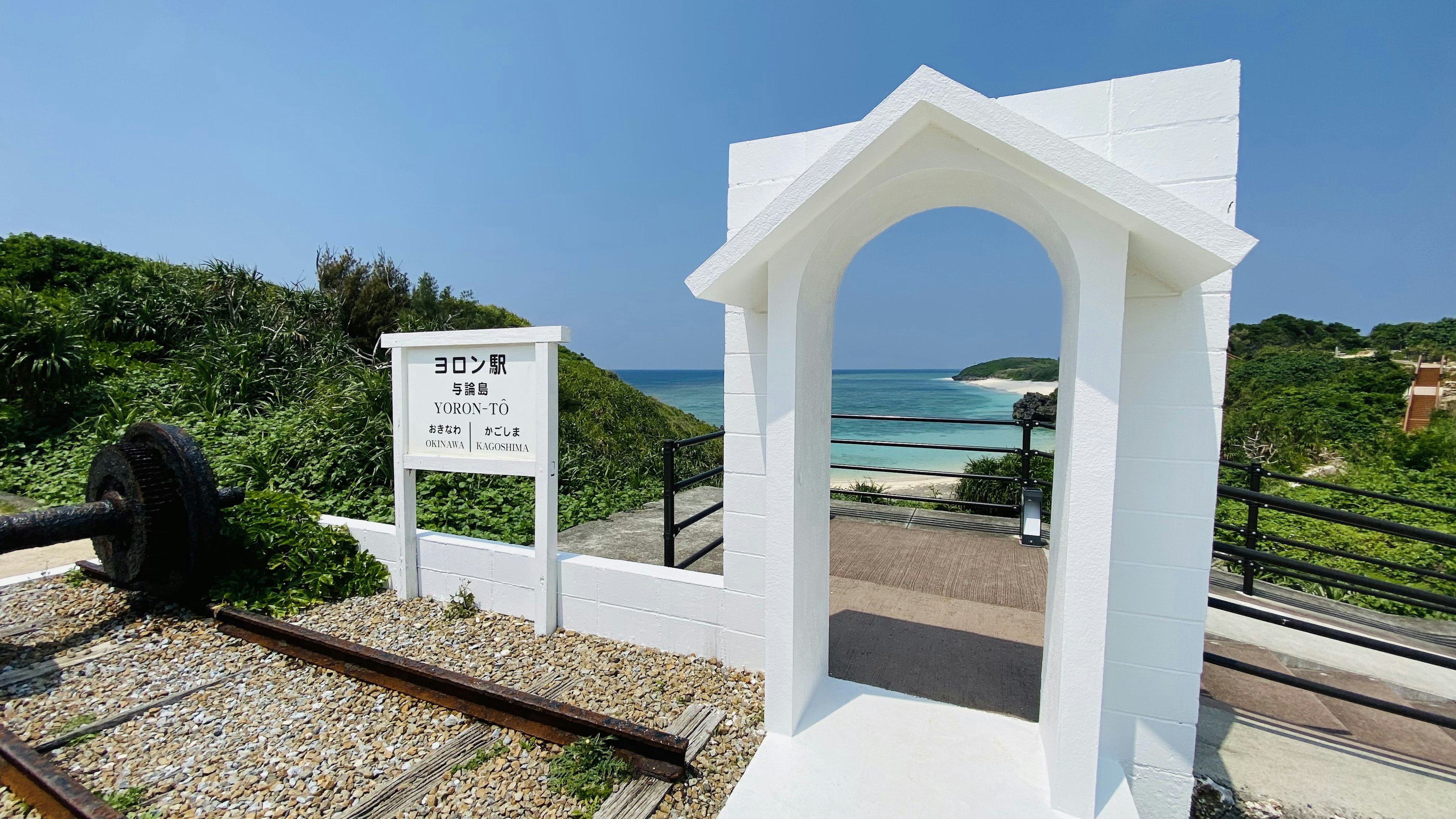 White archway leading to a beach with clear blue sky