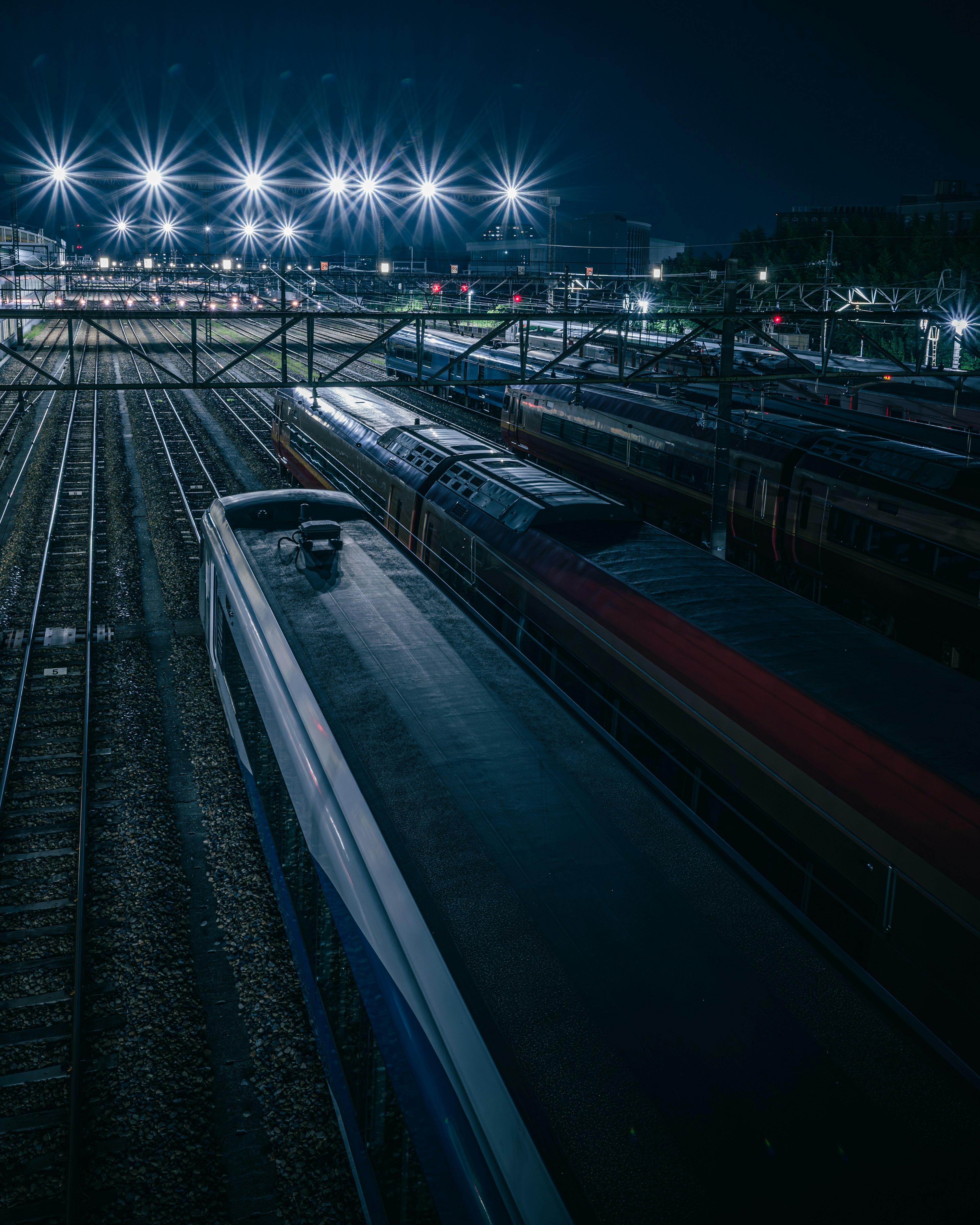 Trains parked at a railway station at night with bright lights