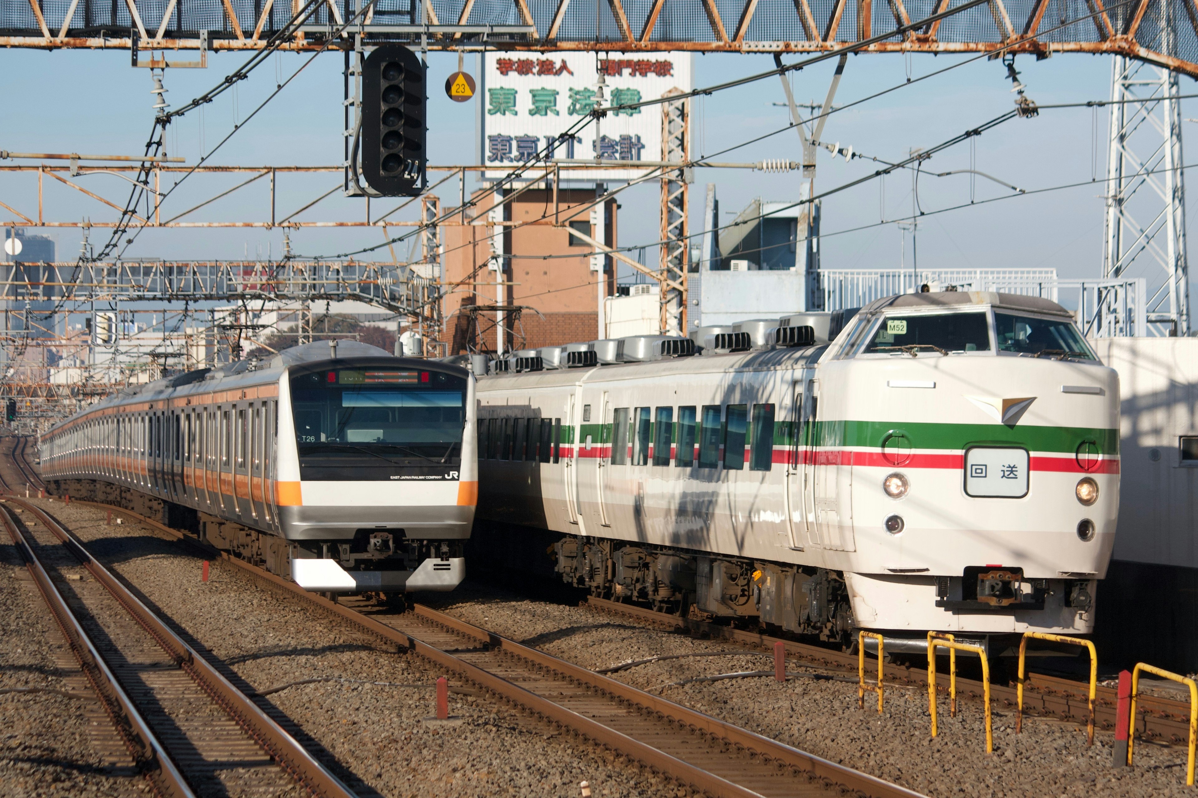 二つの列車が交差する駅の風景 明るい青空と鉄道信号