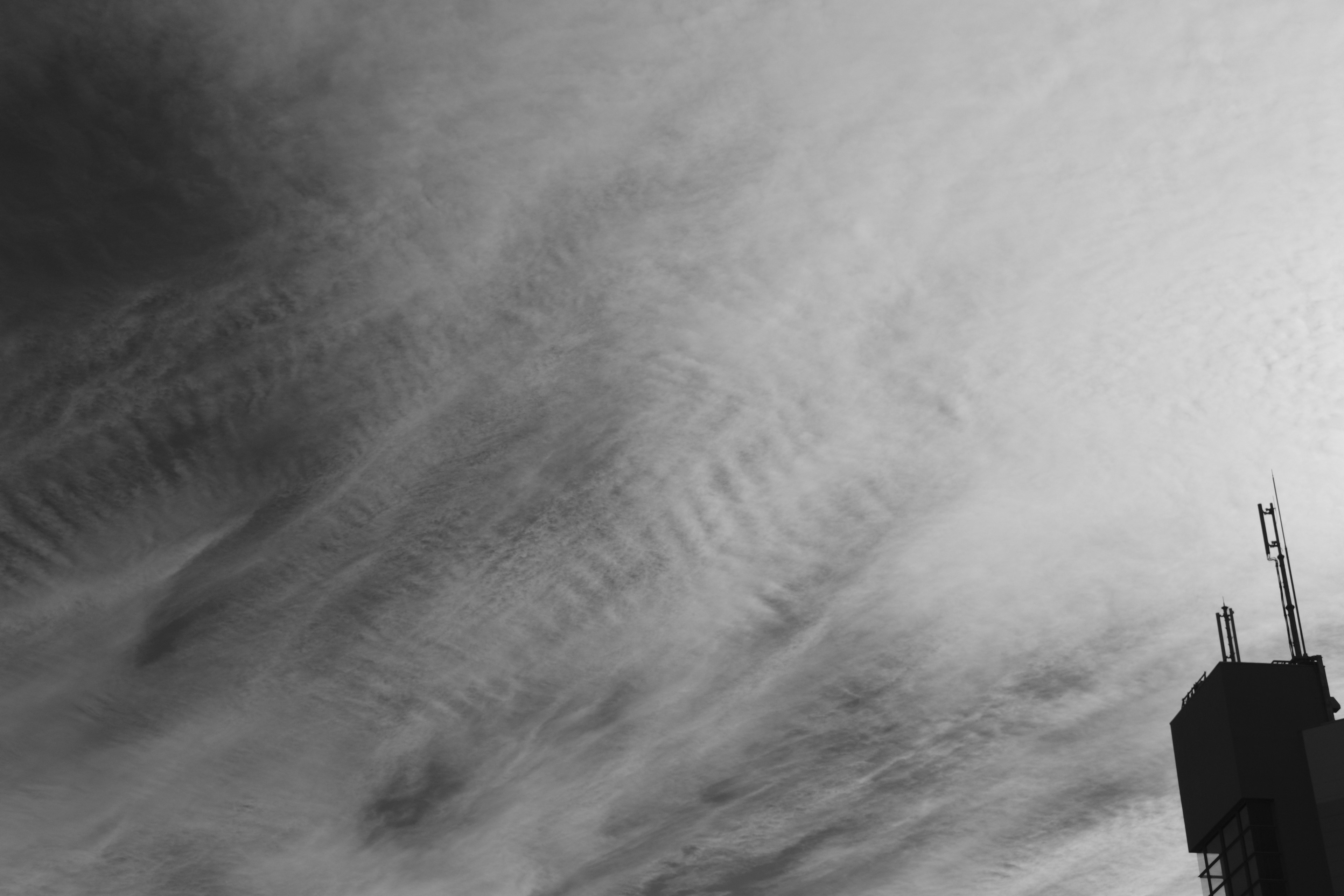 Monochrome sky with clouds and silhouette of a building