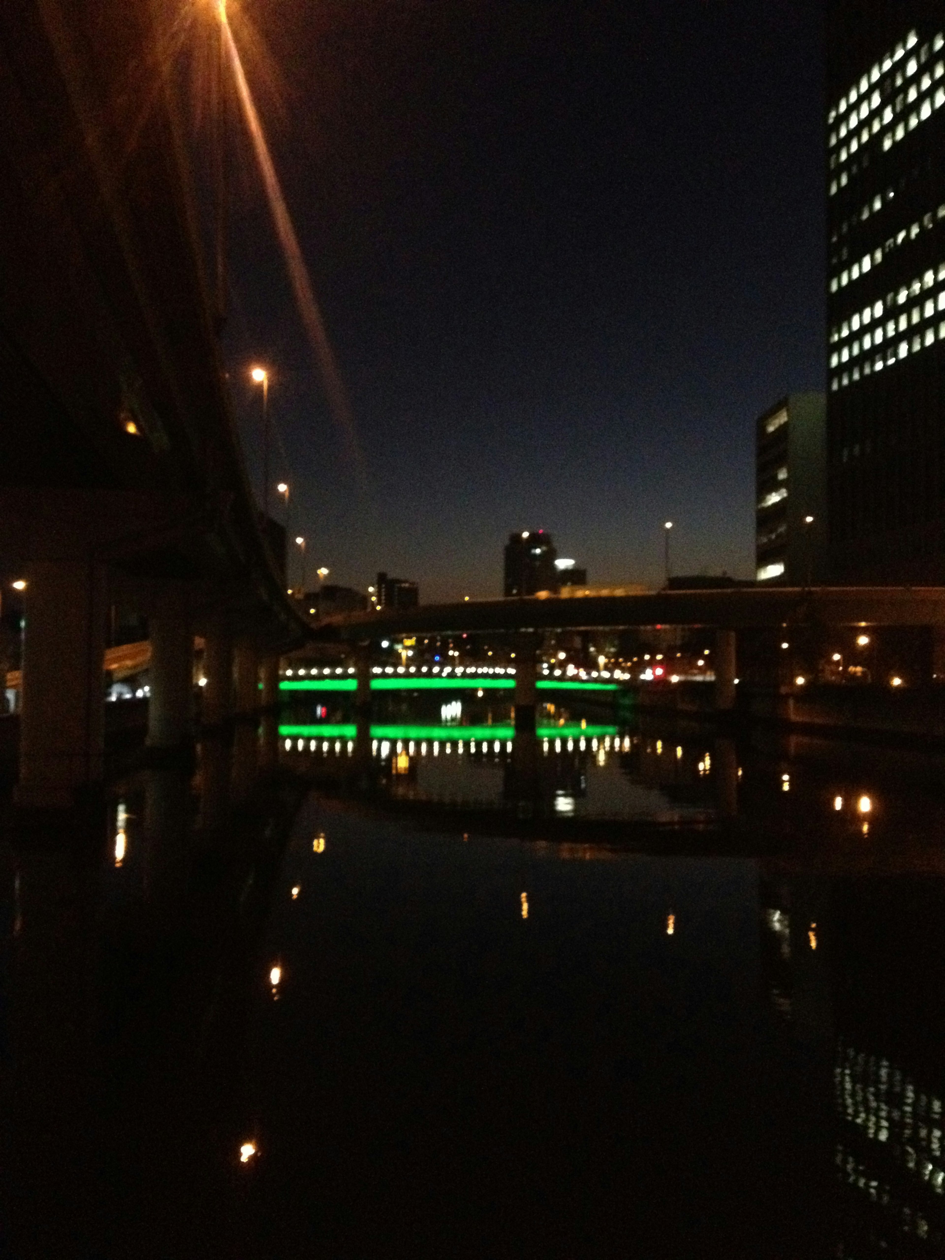 Paysage urbain nocturne avec un pont illuminé et des bâtiments se reflétant dans l'eau