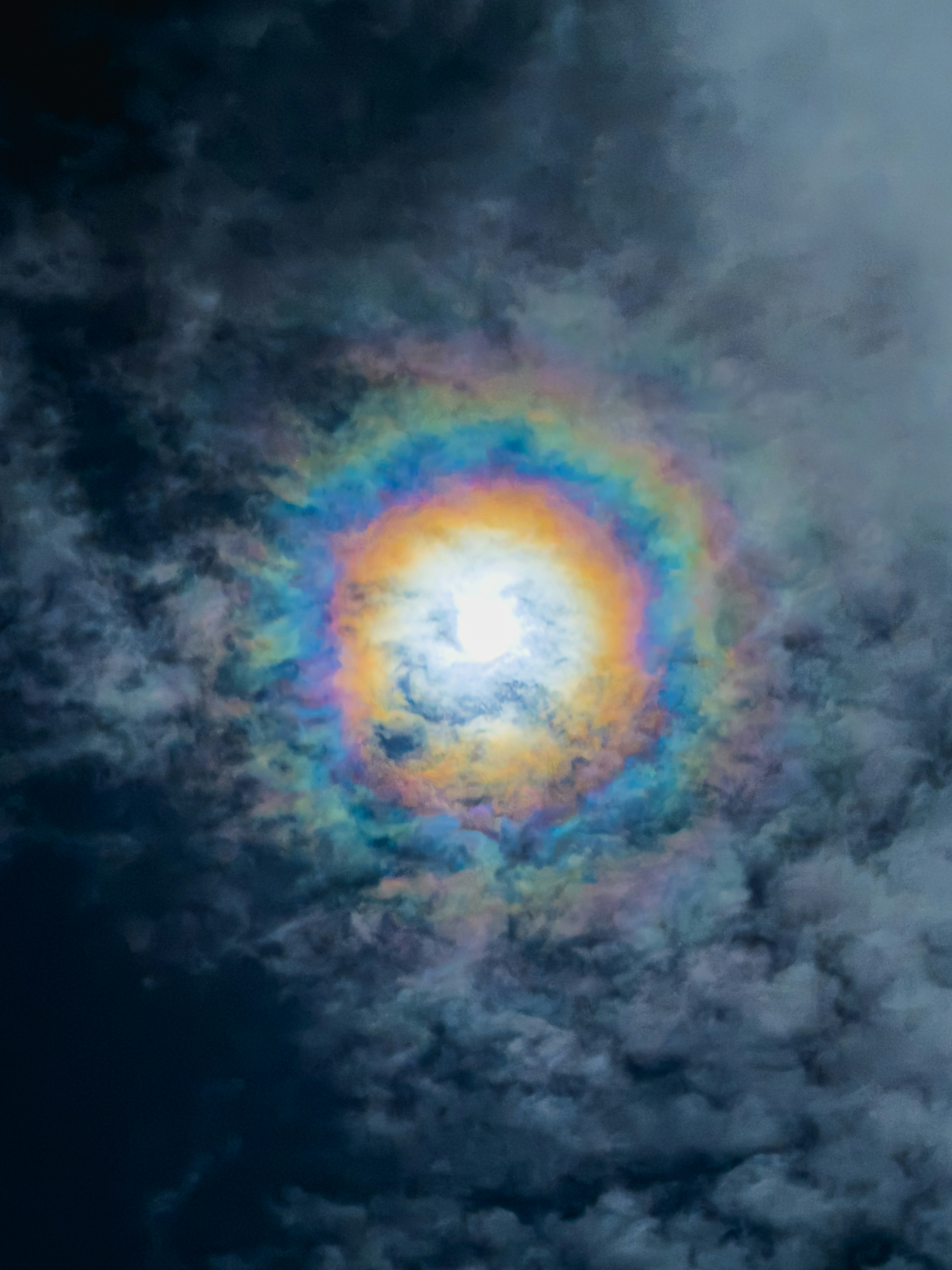 Sol rodeado de un halo colorido en el cielo con nubes