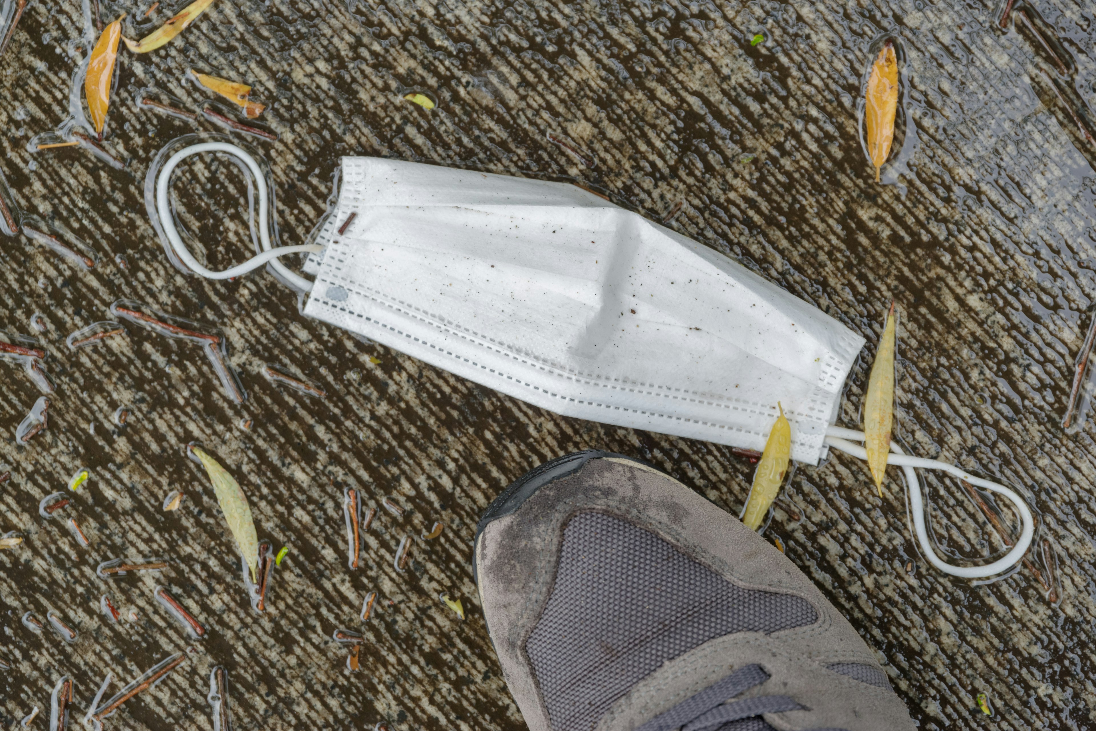 Una mascarilla desechada en el suelo cerca de un zapato