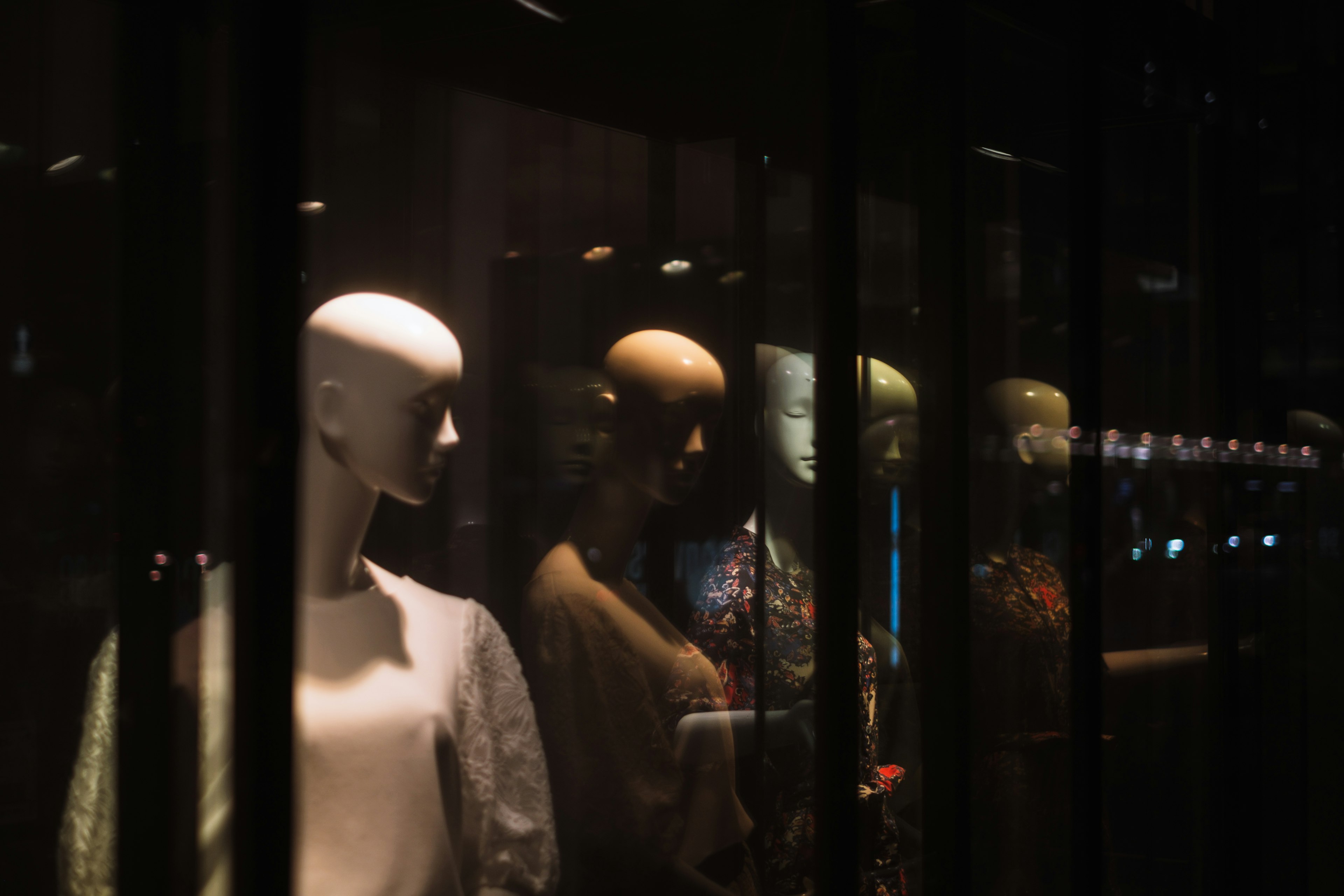 Silhouettes and reflections of mannequins lined up in a display window