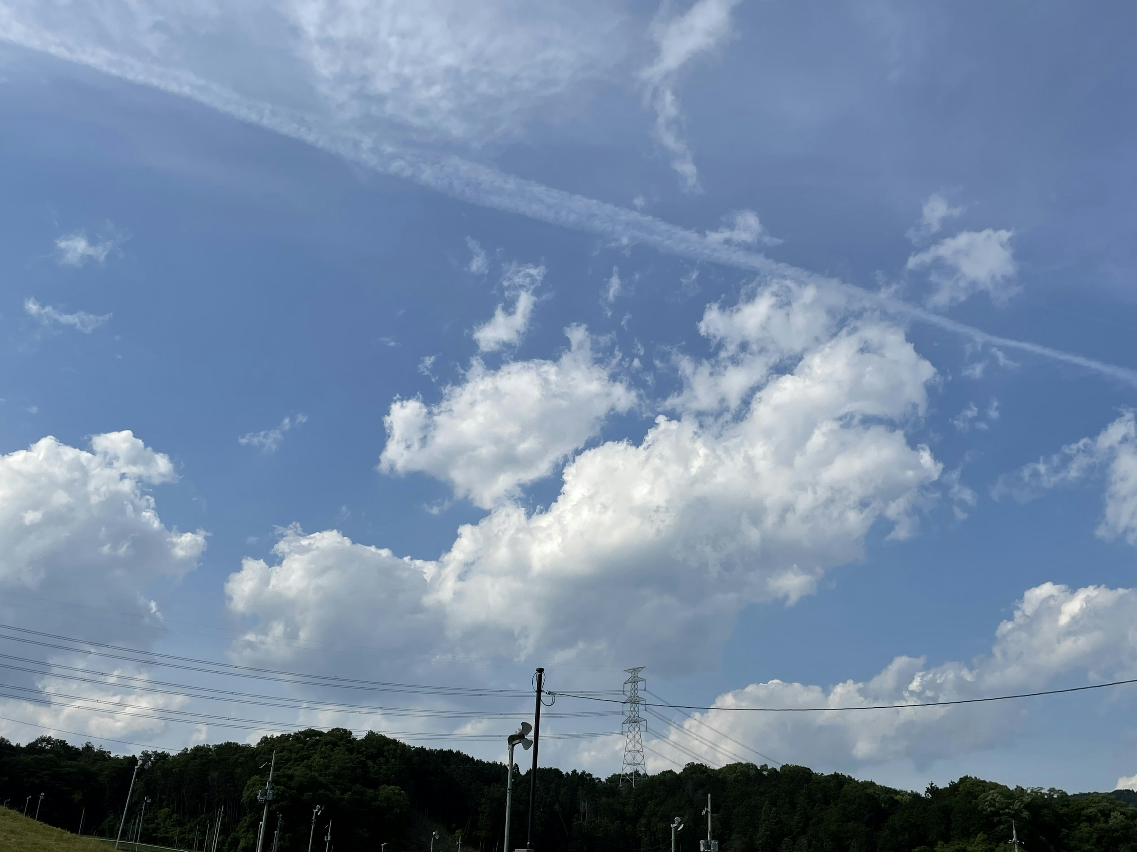 青空と白い雲が広がる風景 緑の丘と電柱が見える