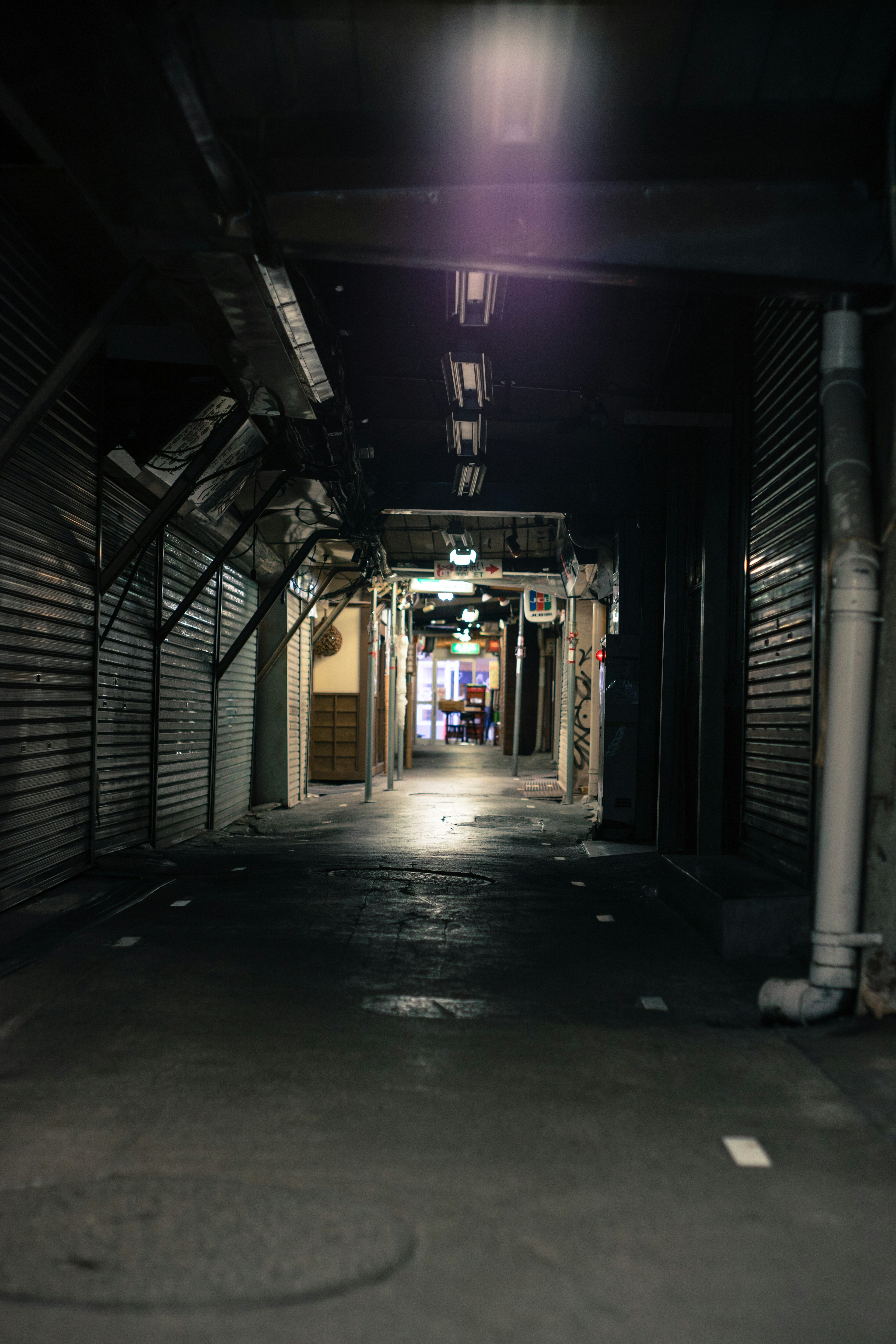 Dark passageway leading to a lit commercial area