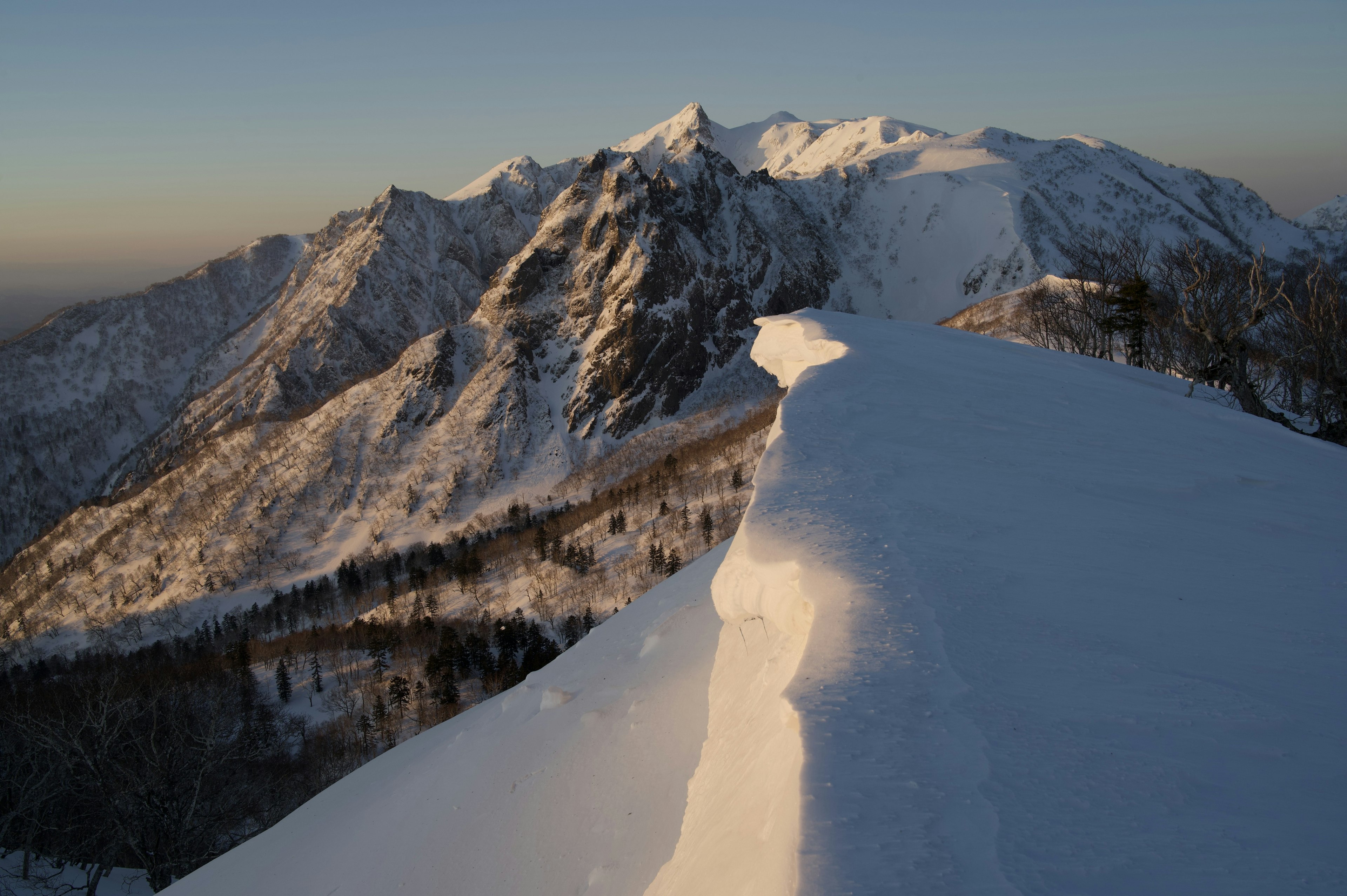 Paysage montagneux enneigé avec une douce lumière de coucher de soleil