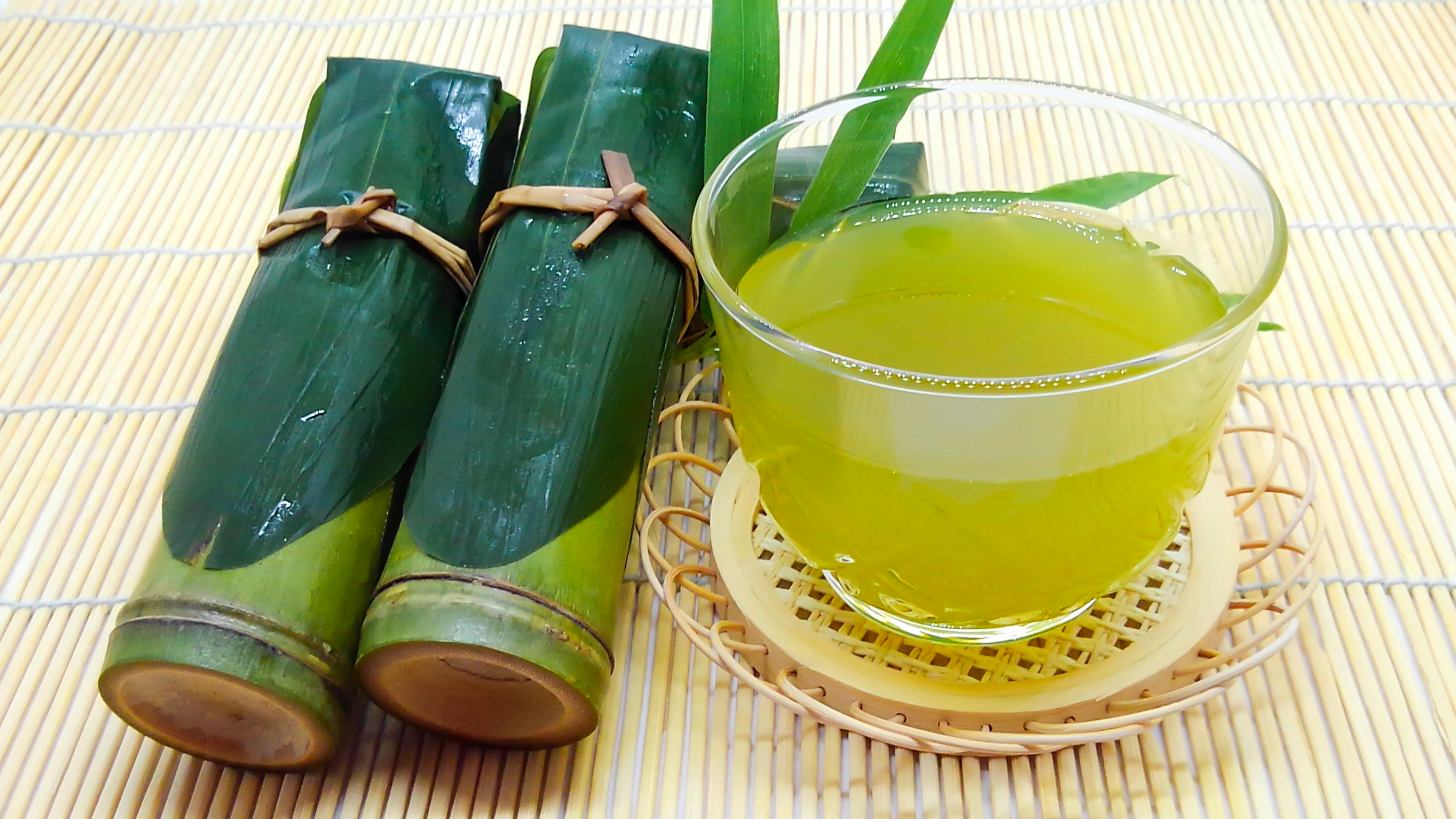 緑茶の飲み物と竹の葉で包まれたスナックが並んでいる画像