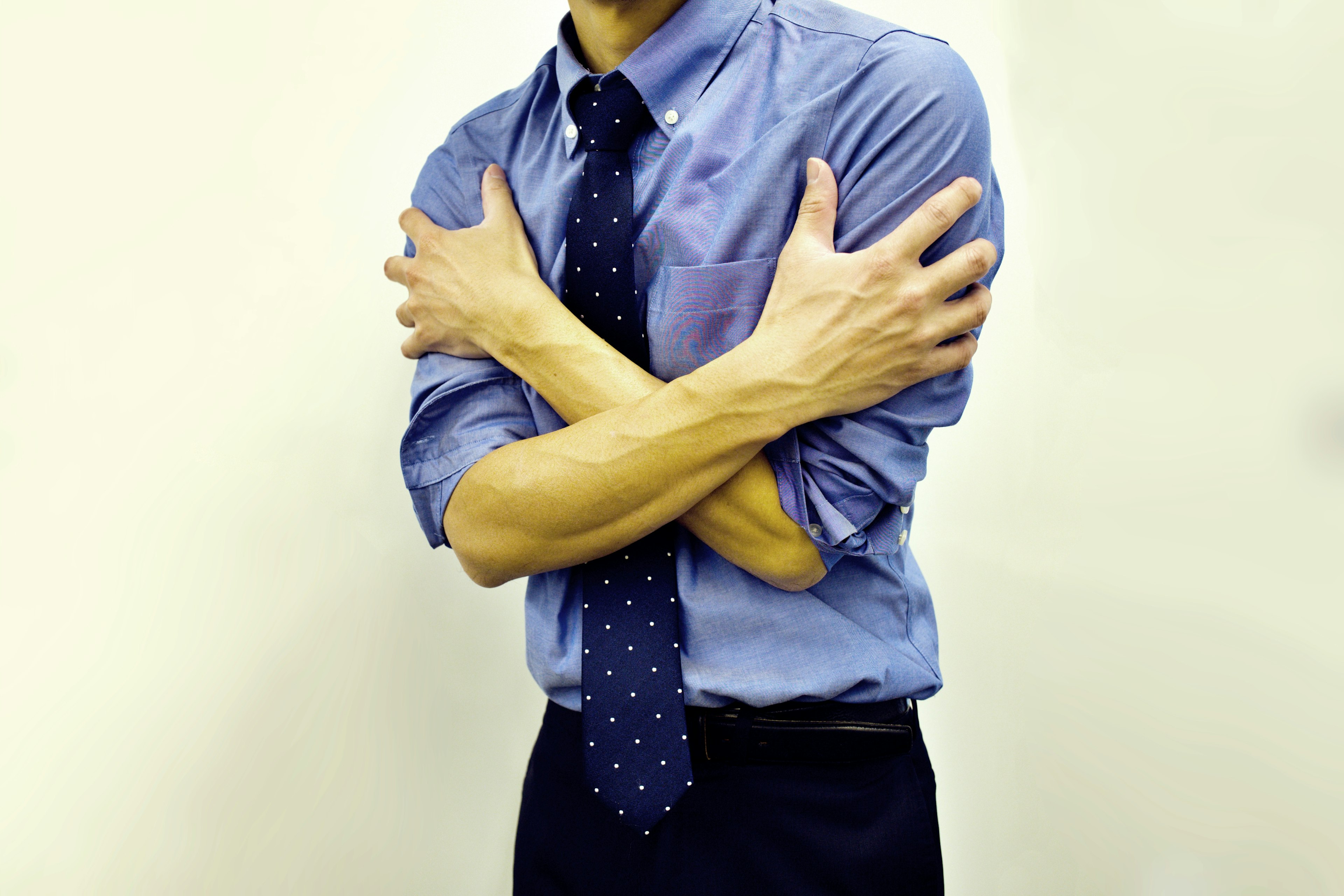 Man in blue shirt hugging himself with crossed arms