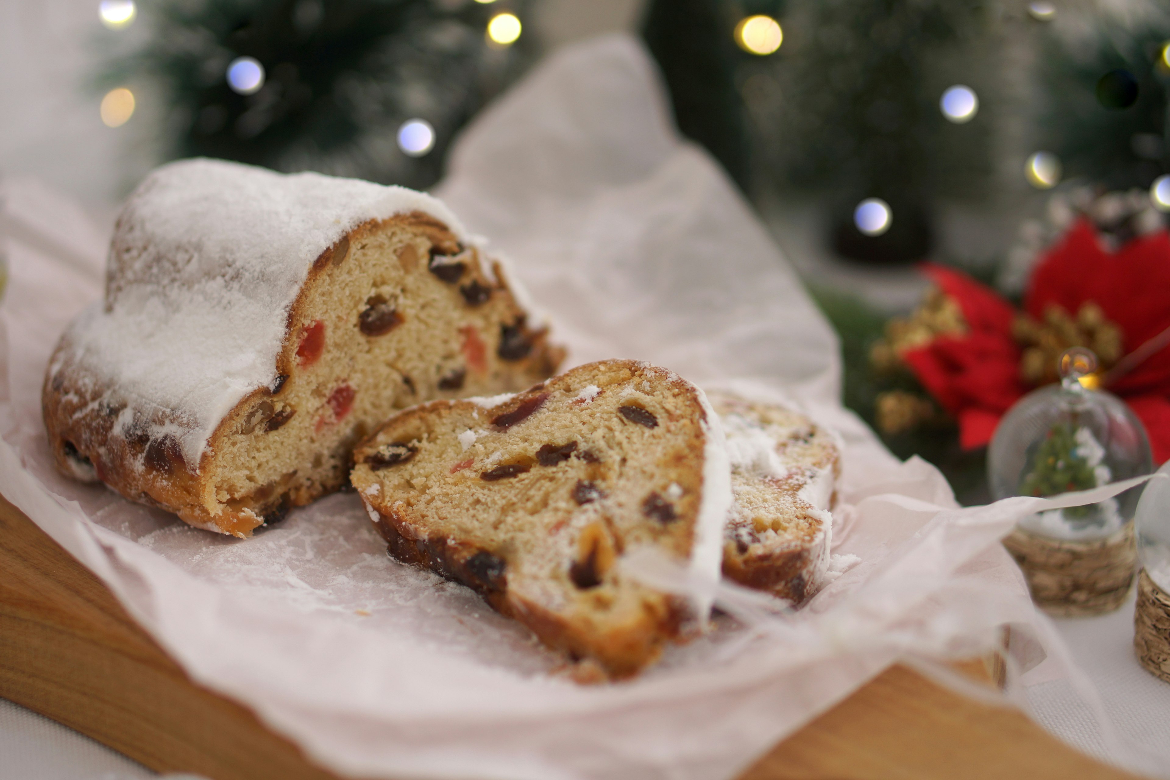 Slice of Christmas stollen dusted with powdered sugar on a wooden board