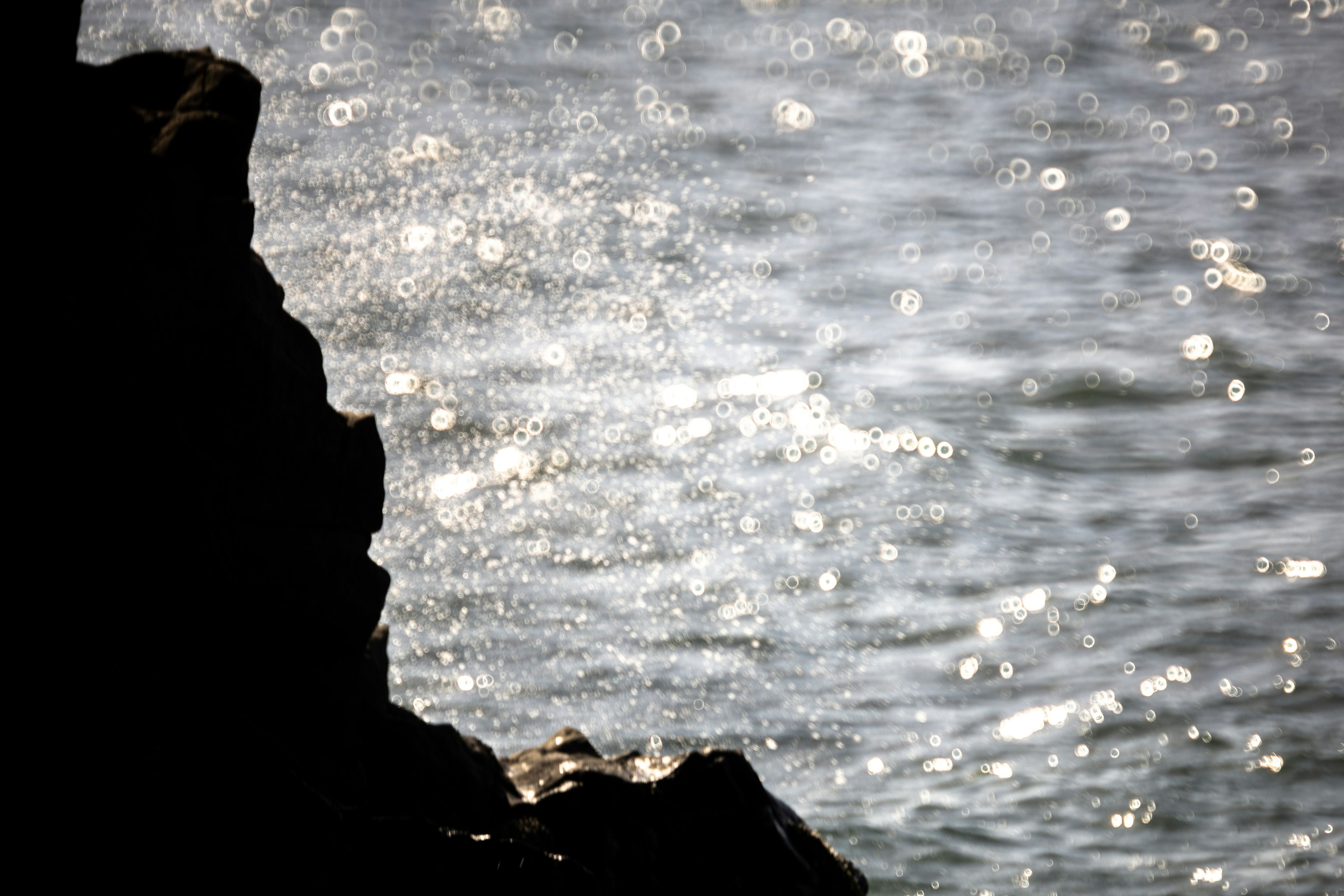 Silhouette eines Felsens mit schimmernden Wasserwellen