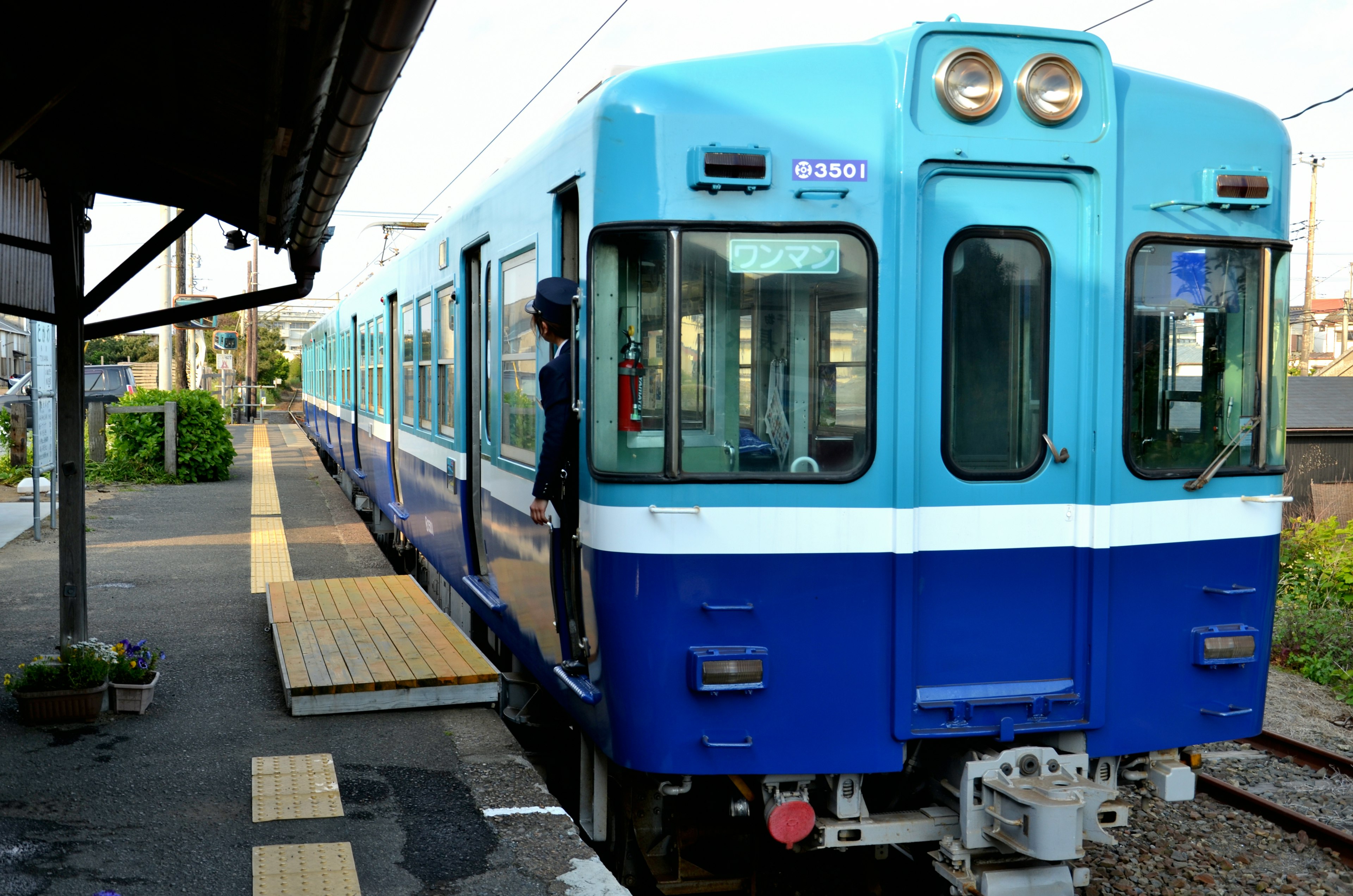 青と白の列車が駅のプラットフォームに停車している