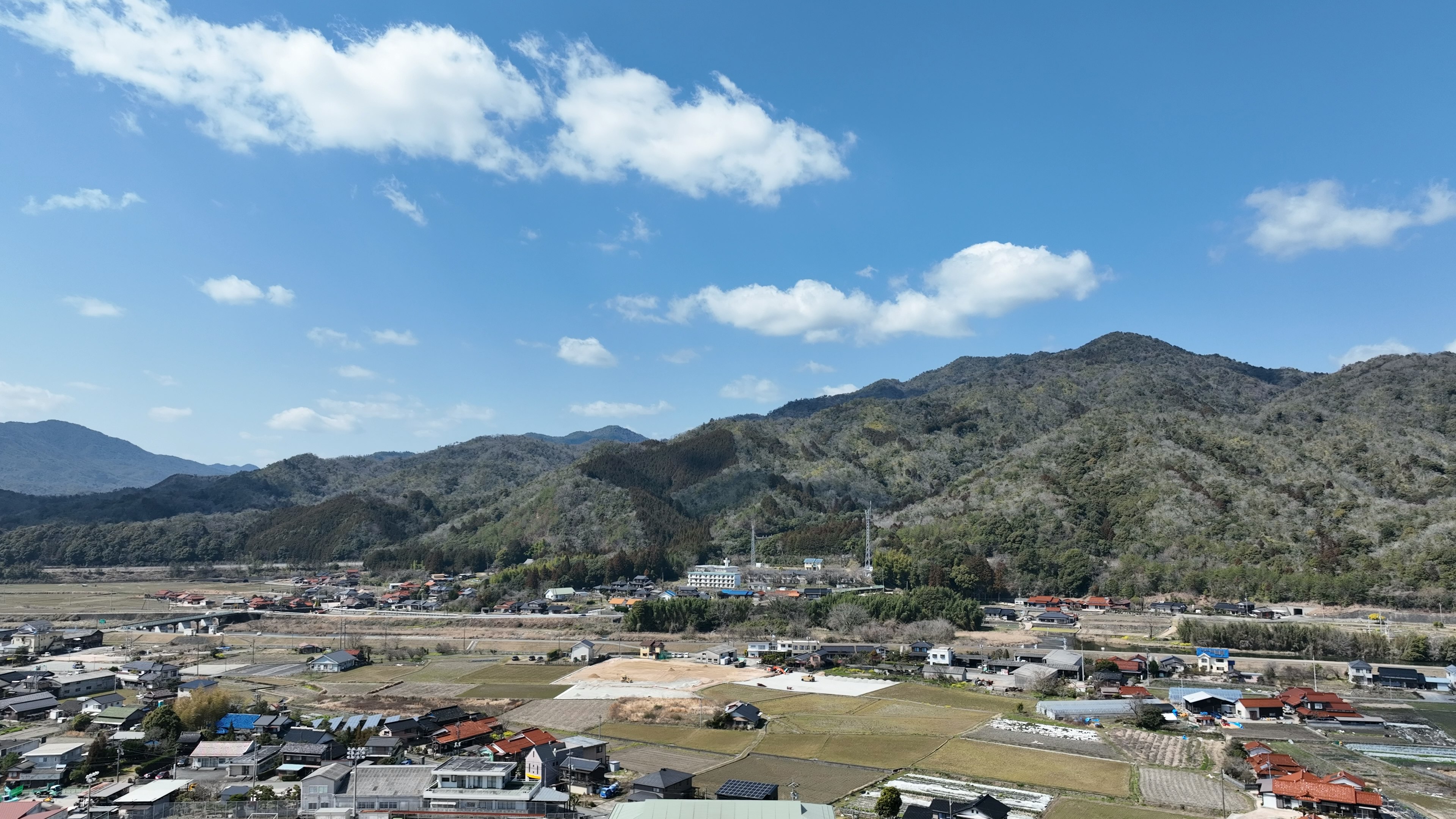 Vista escénica de montañas y cielo azul con un pequeño pueblo y un sitio de construcción