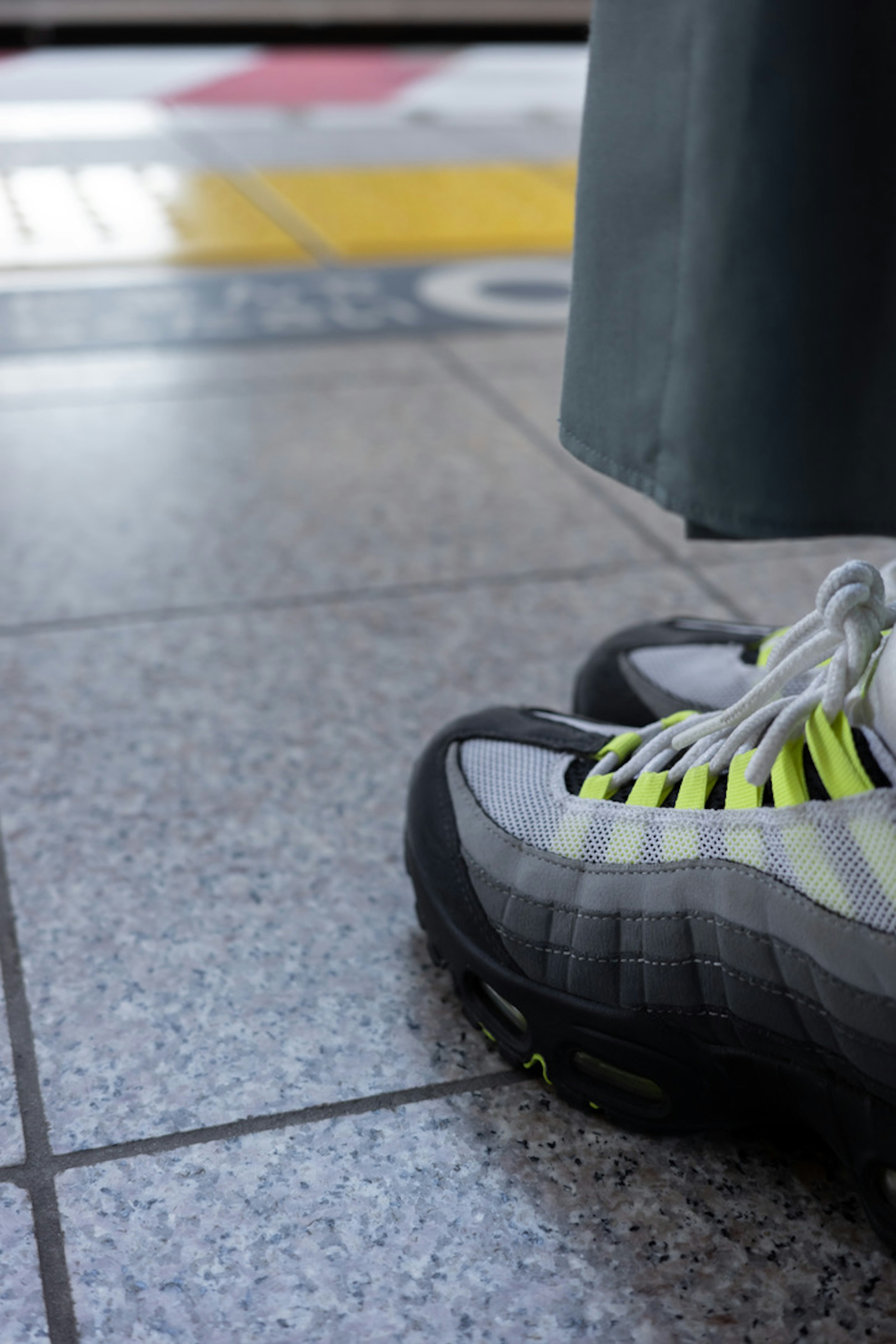 Baskets grises avec des accents néon à côté d'un sol carrelé