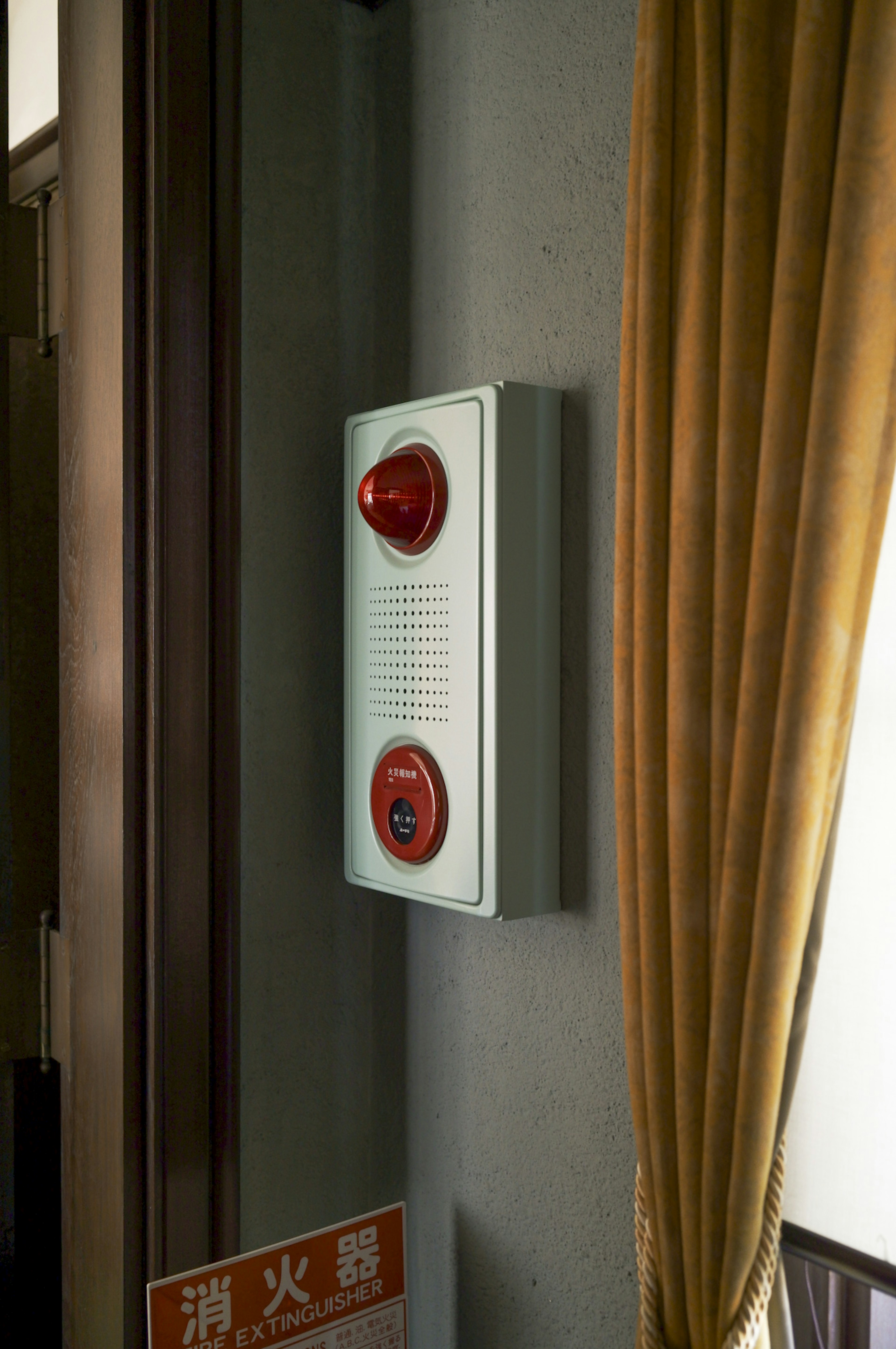 A wall-mounted alarm device with two red buttons