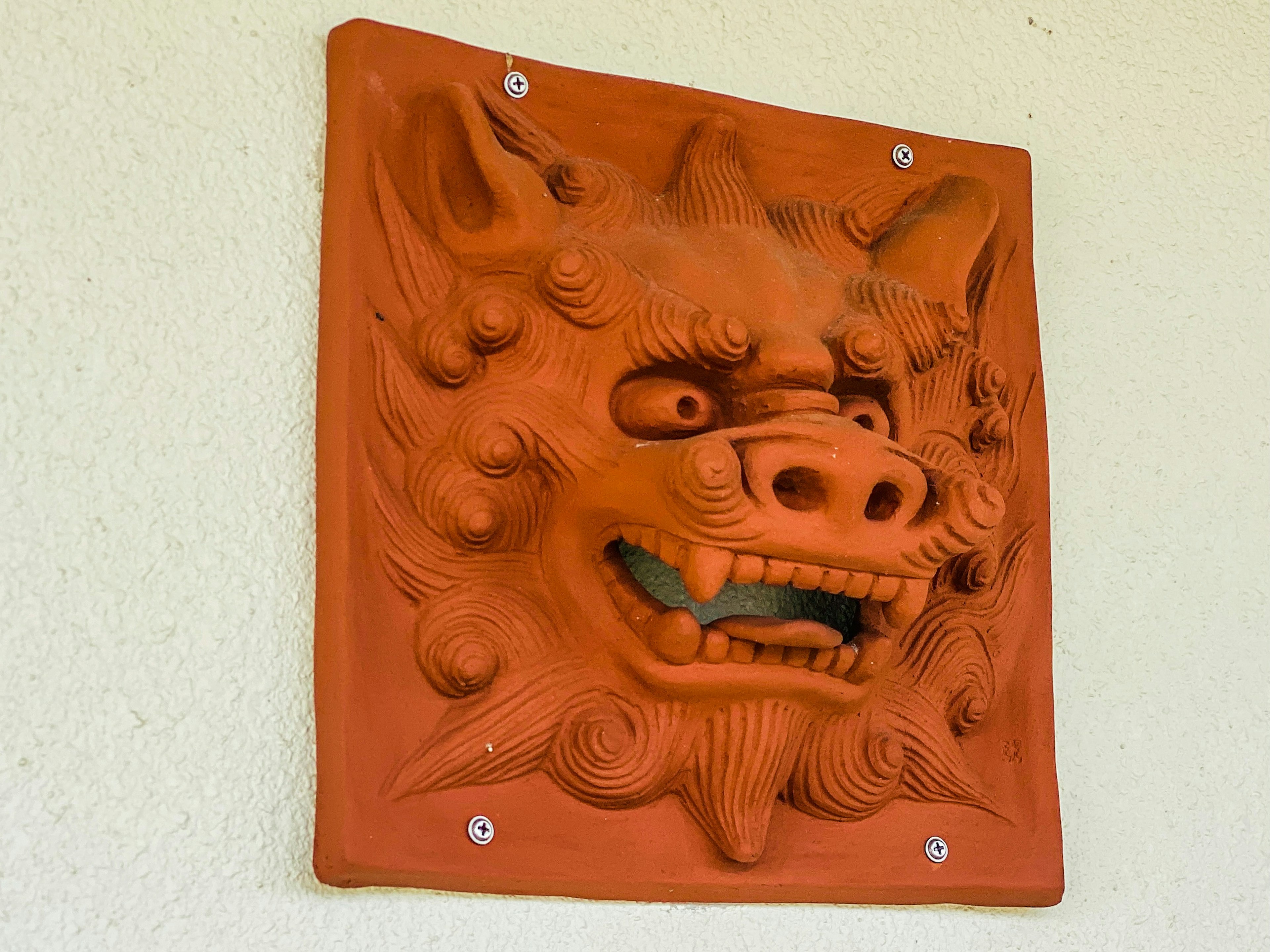 An orange ceramic lion head sculpture mounted on a wall