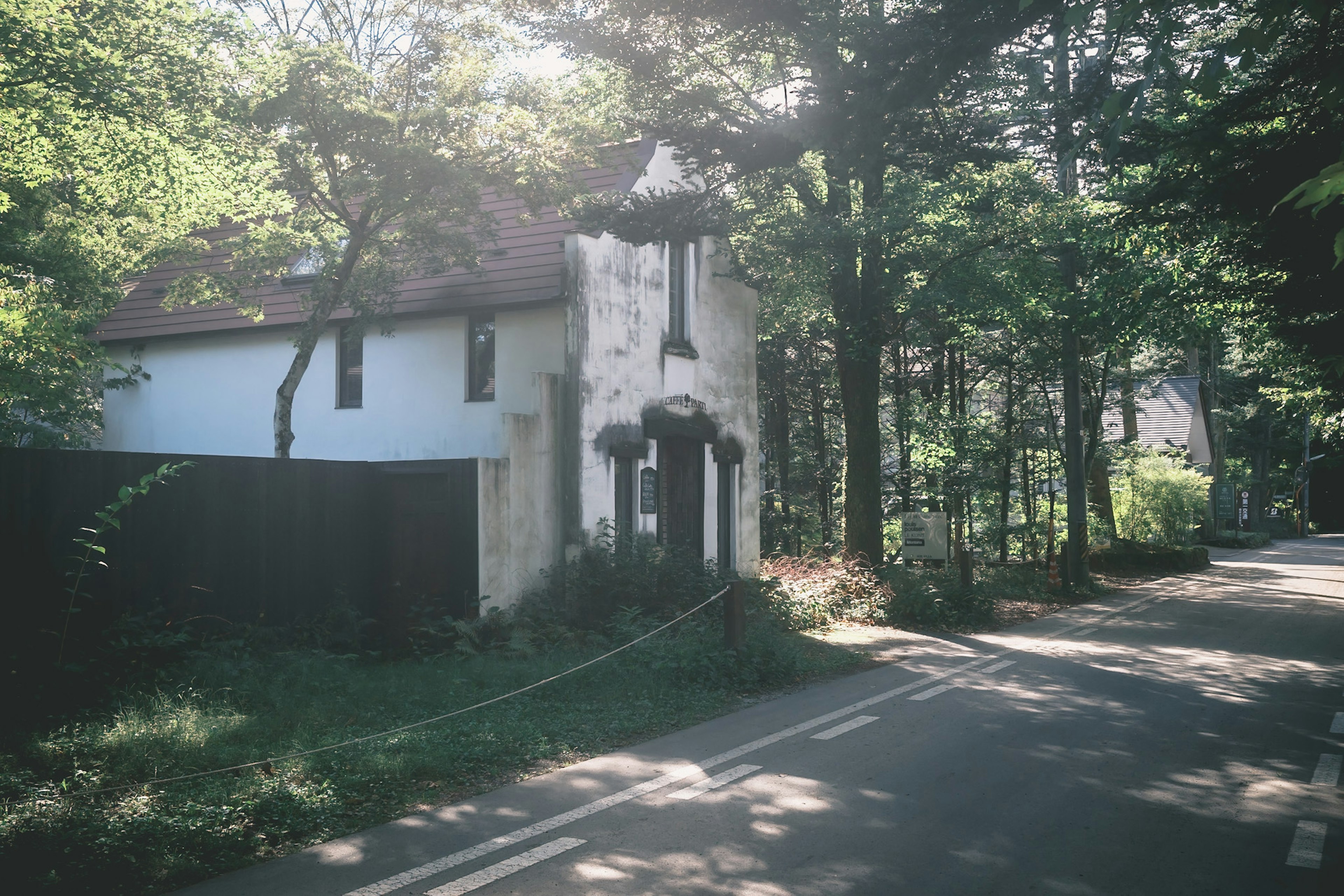 Altes Haus umgeben von Grün mit einer nahegelegenen Straße