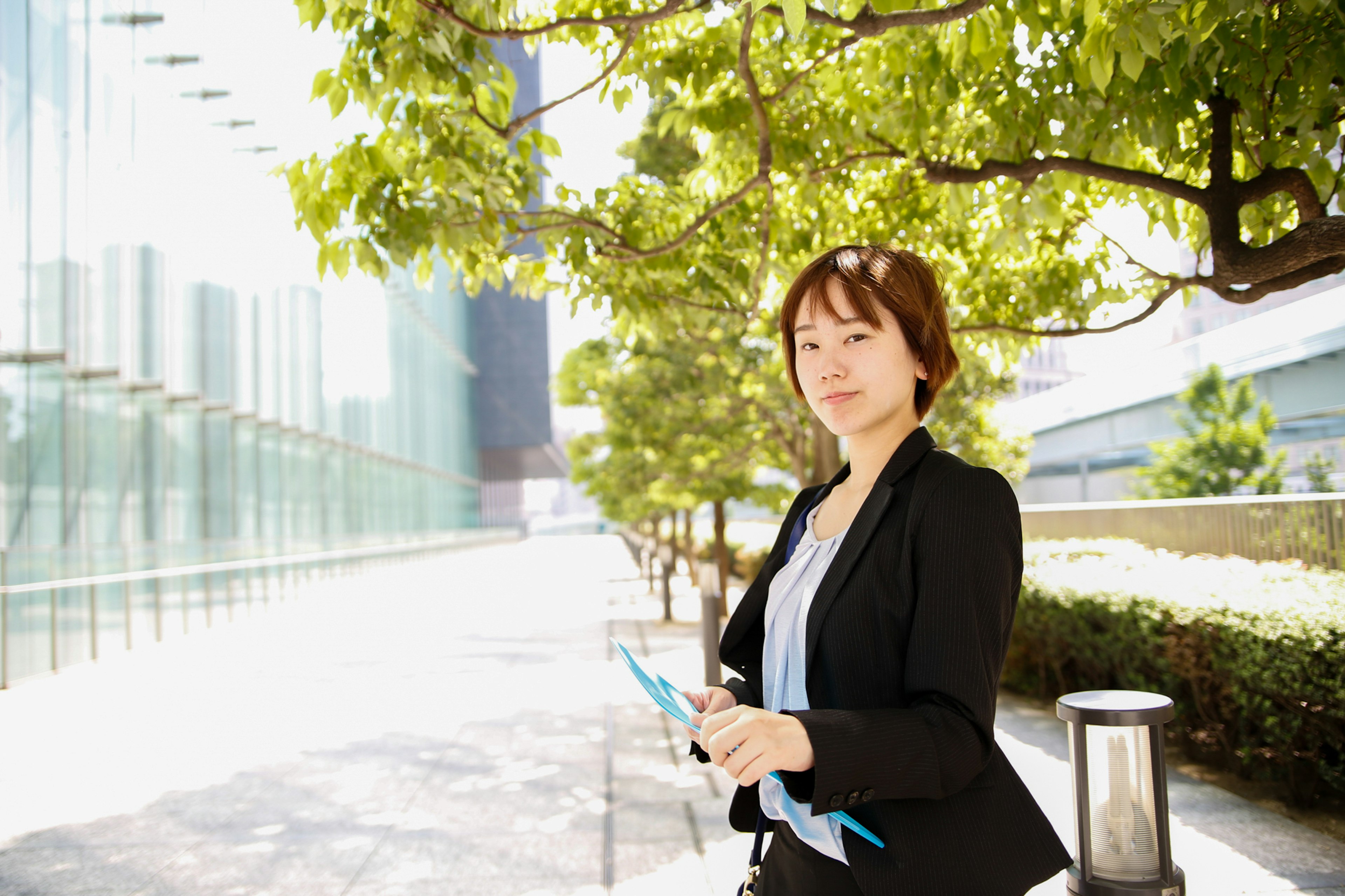 A woman in a business suit standing in sunlight outdoors