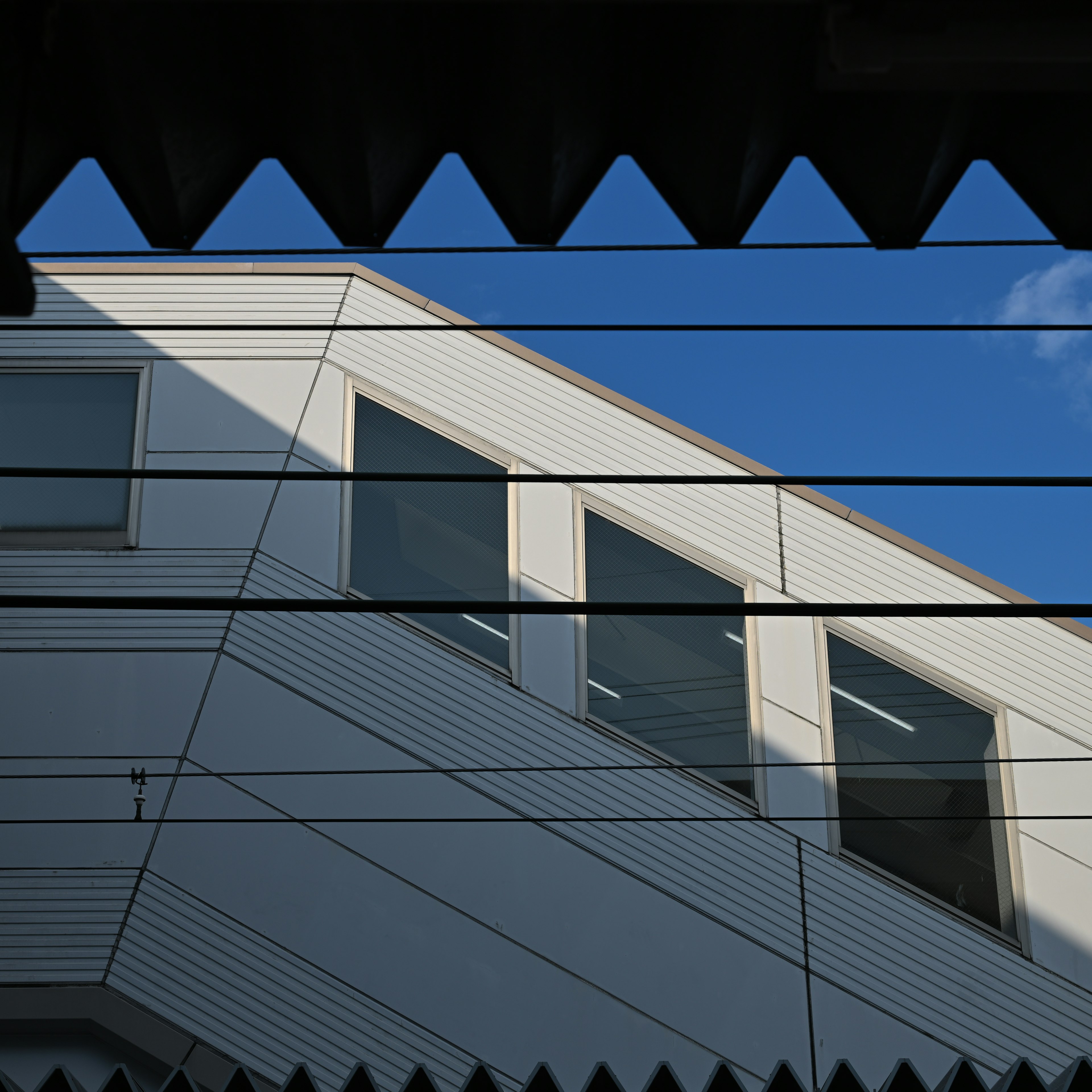 Esterno di un edificio moderno sotto un cielo blu con finestre e tetto angolato