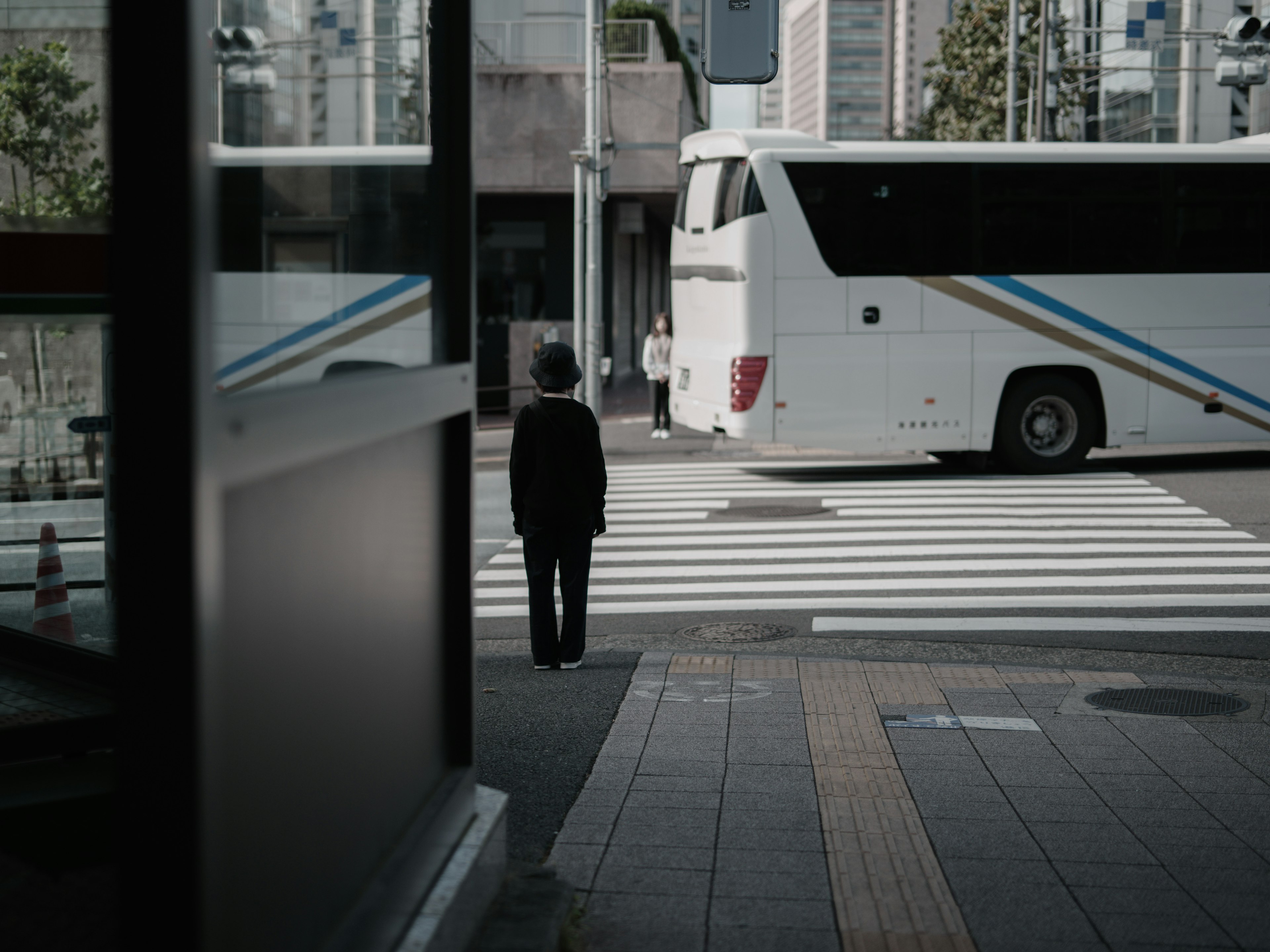 一个人在城市环境中过马路，旁边有一辆公交车