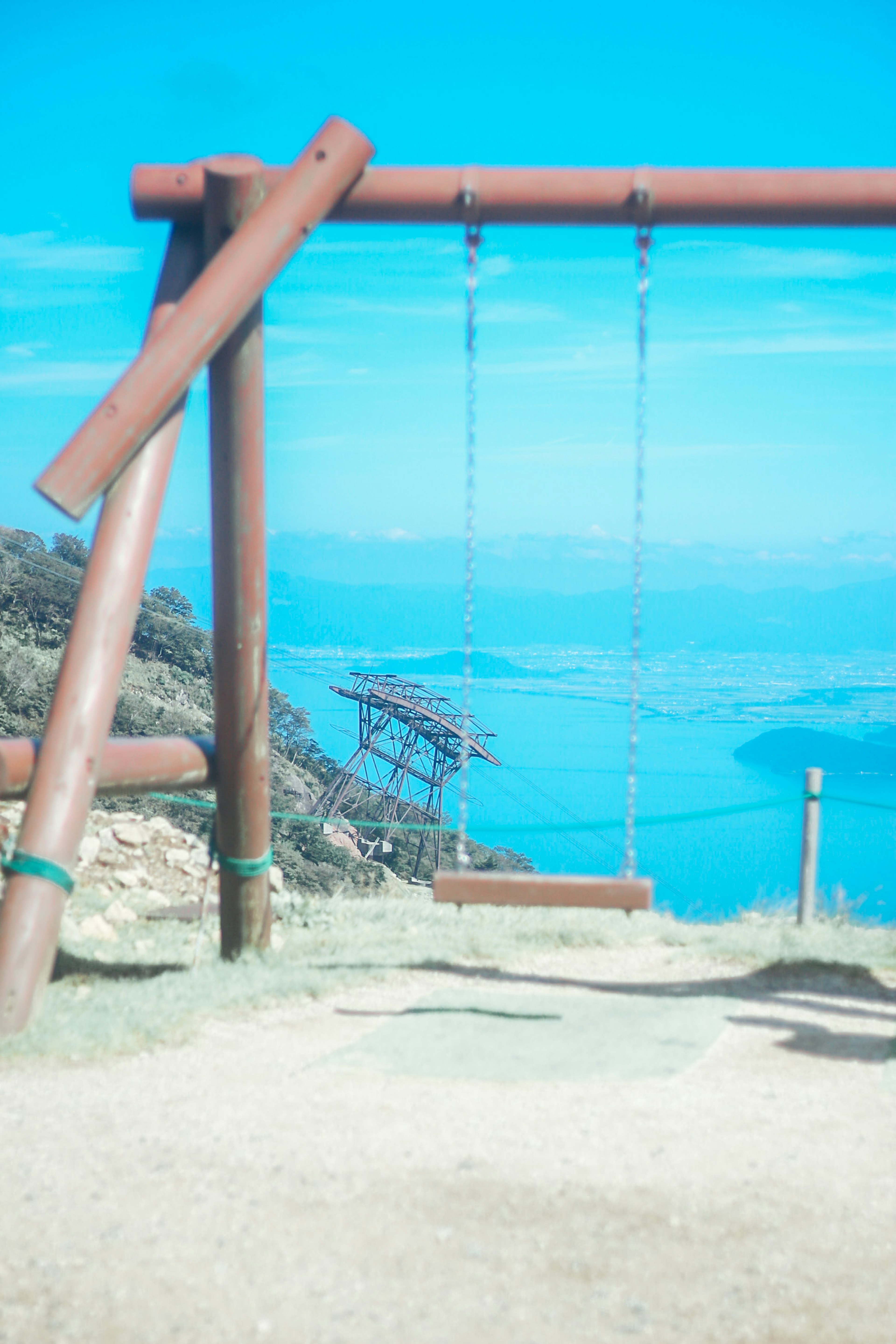 Wooden swing in a landscape with a blue sky and ocean in the background