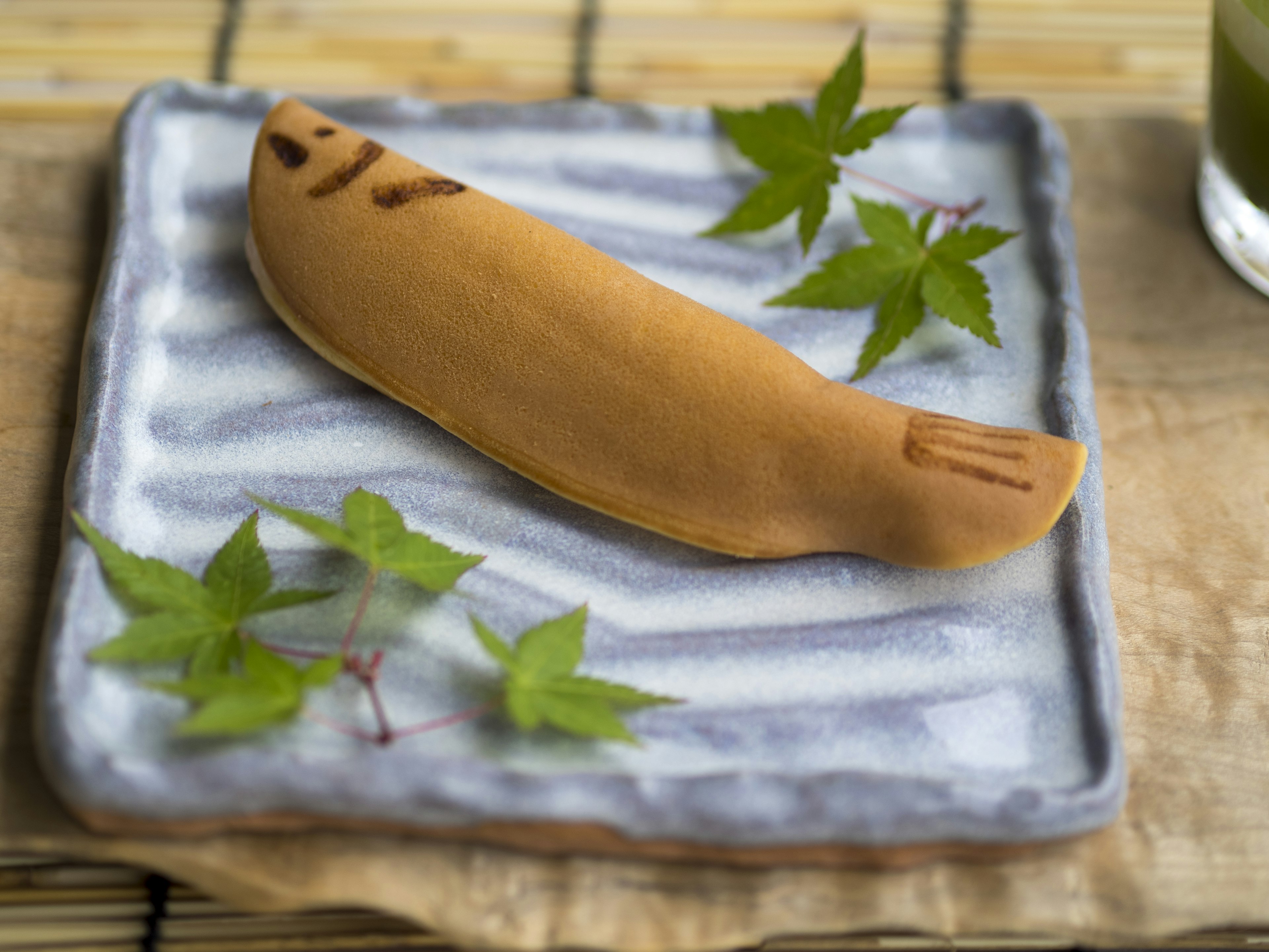 Fish-shaped wagashi dessert placed on a plate with leaves