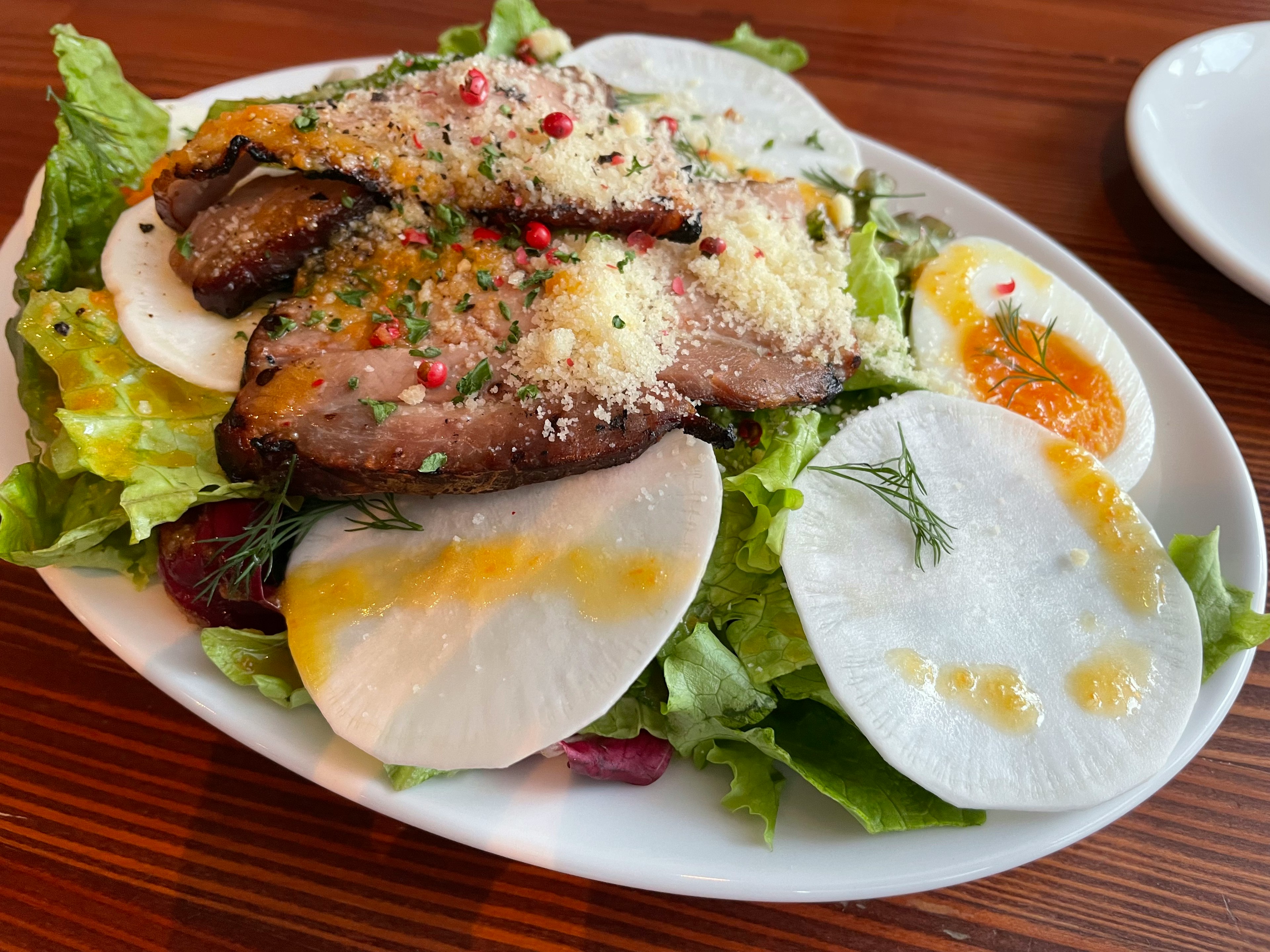 Fresh salad topped with sliced meat and eggs