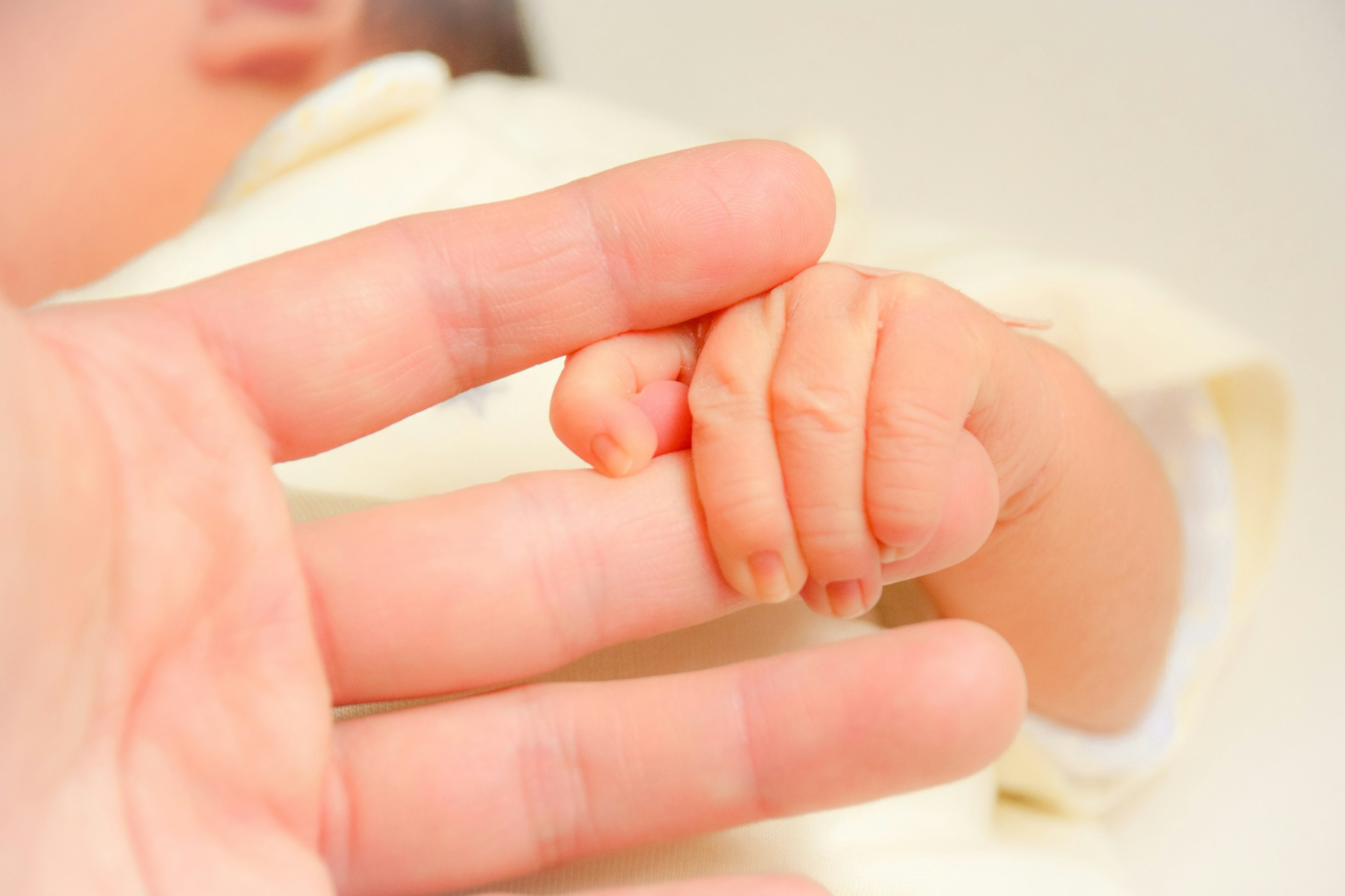 A baby hand grasping an adult finger in a tender moment